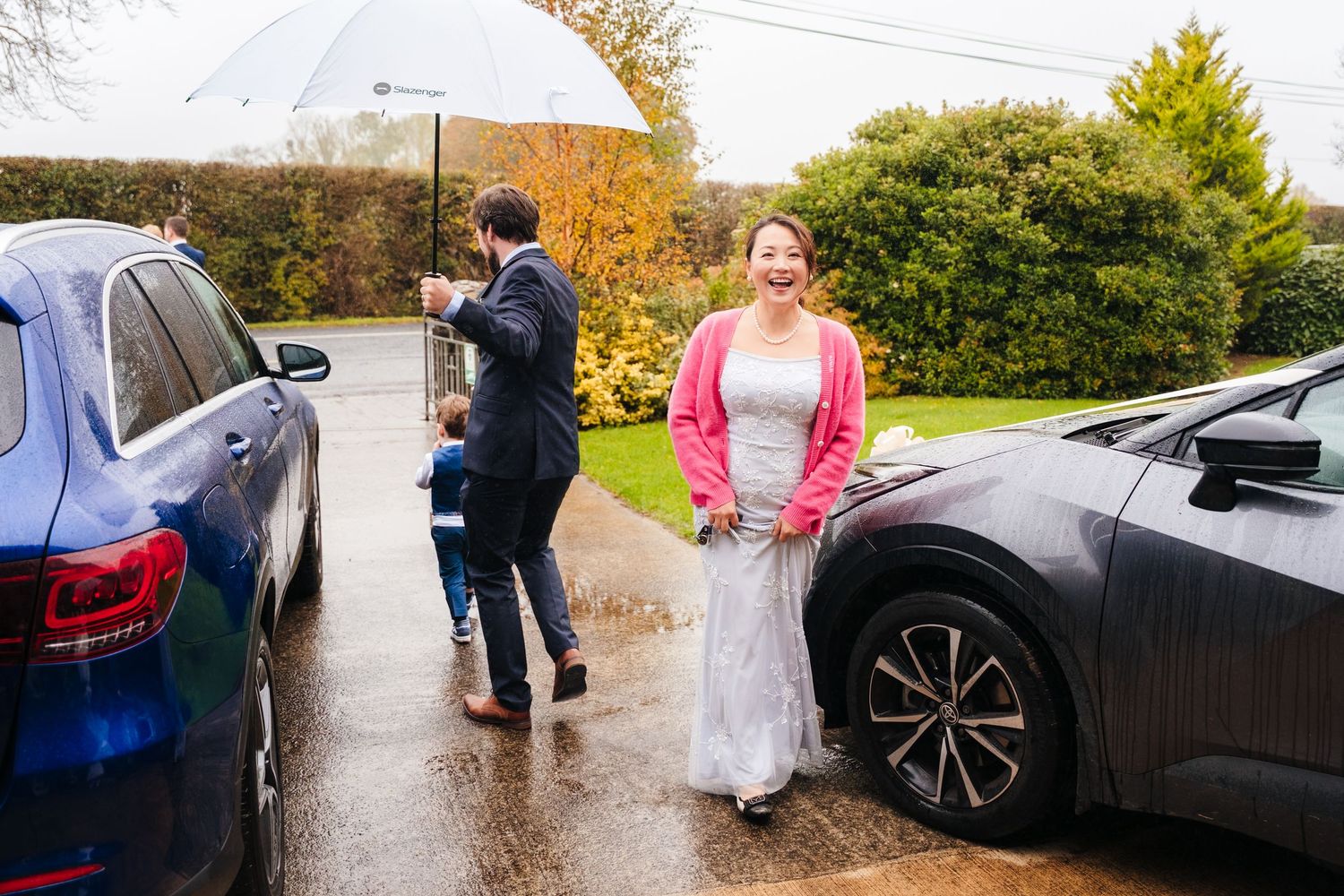 A sequence of candid moments captured during a rainy autumn wedding day with umbrellas and cars in the background.