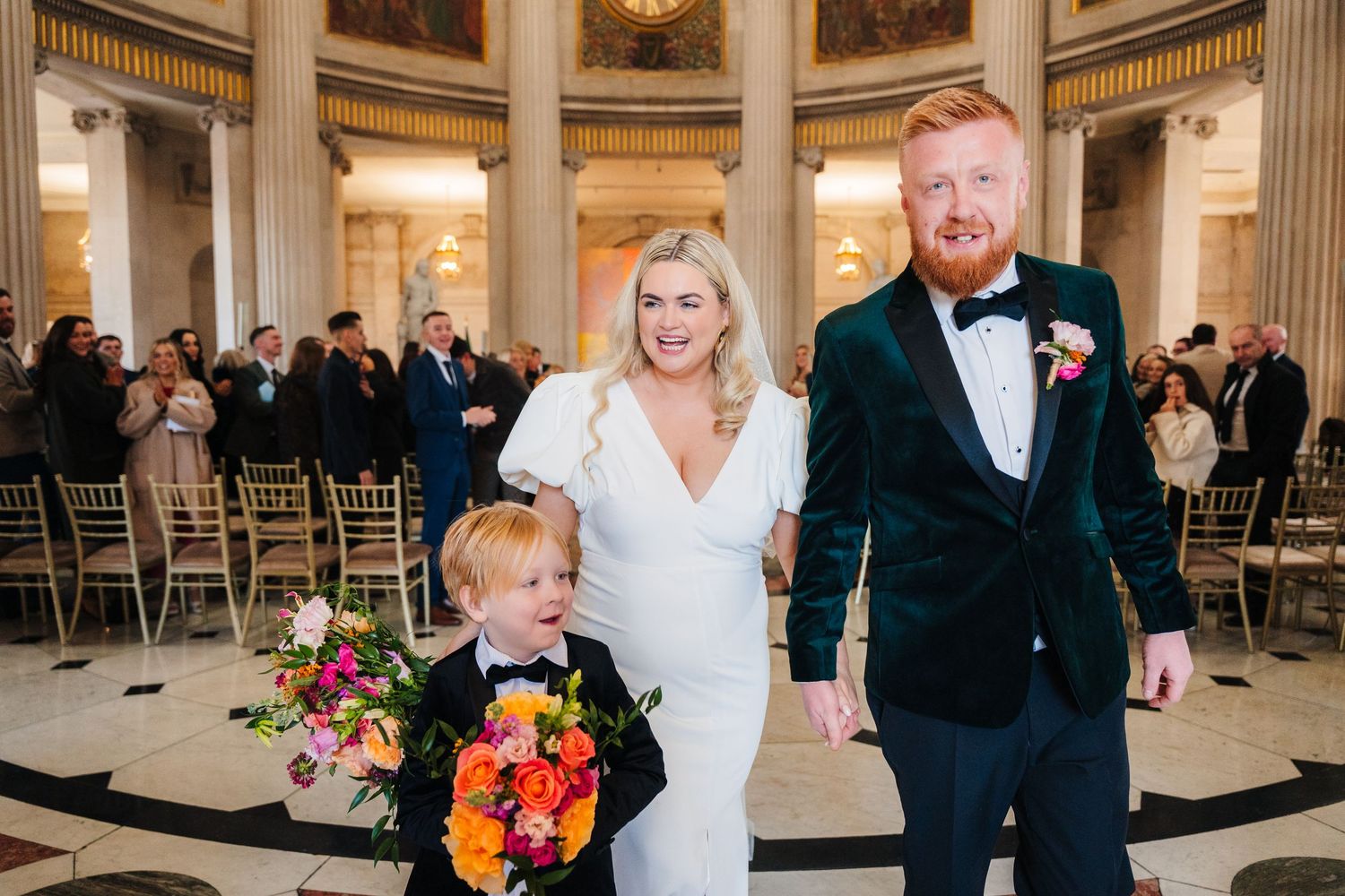 Elegant wedding ceremony takes place in a grand columned hall with ornate architectural details. Wedding photographer dublin