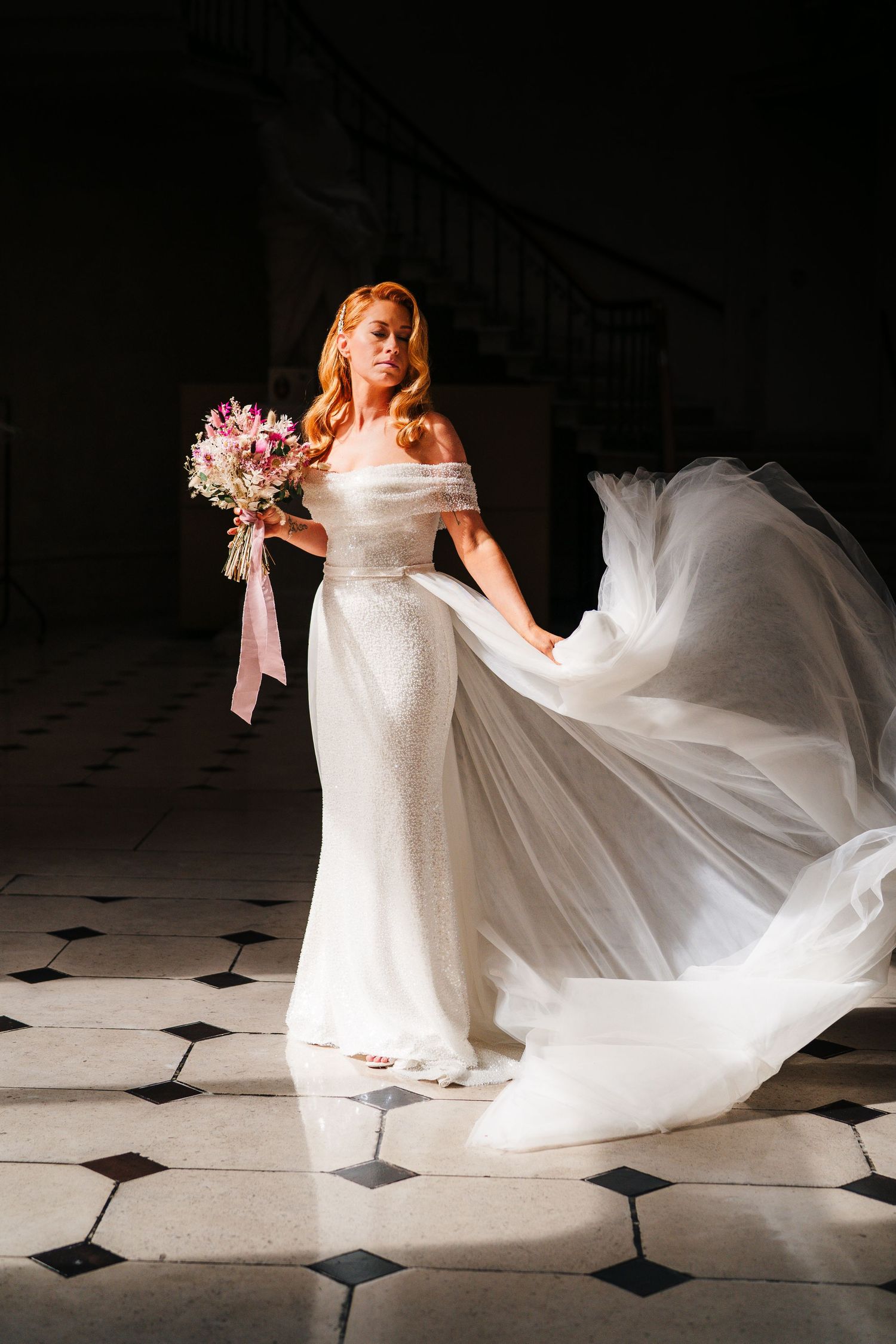 Bride in flowing white dress holds pink bouquet while posing on checkered floor. city hall dublin wedding photos