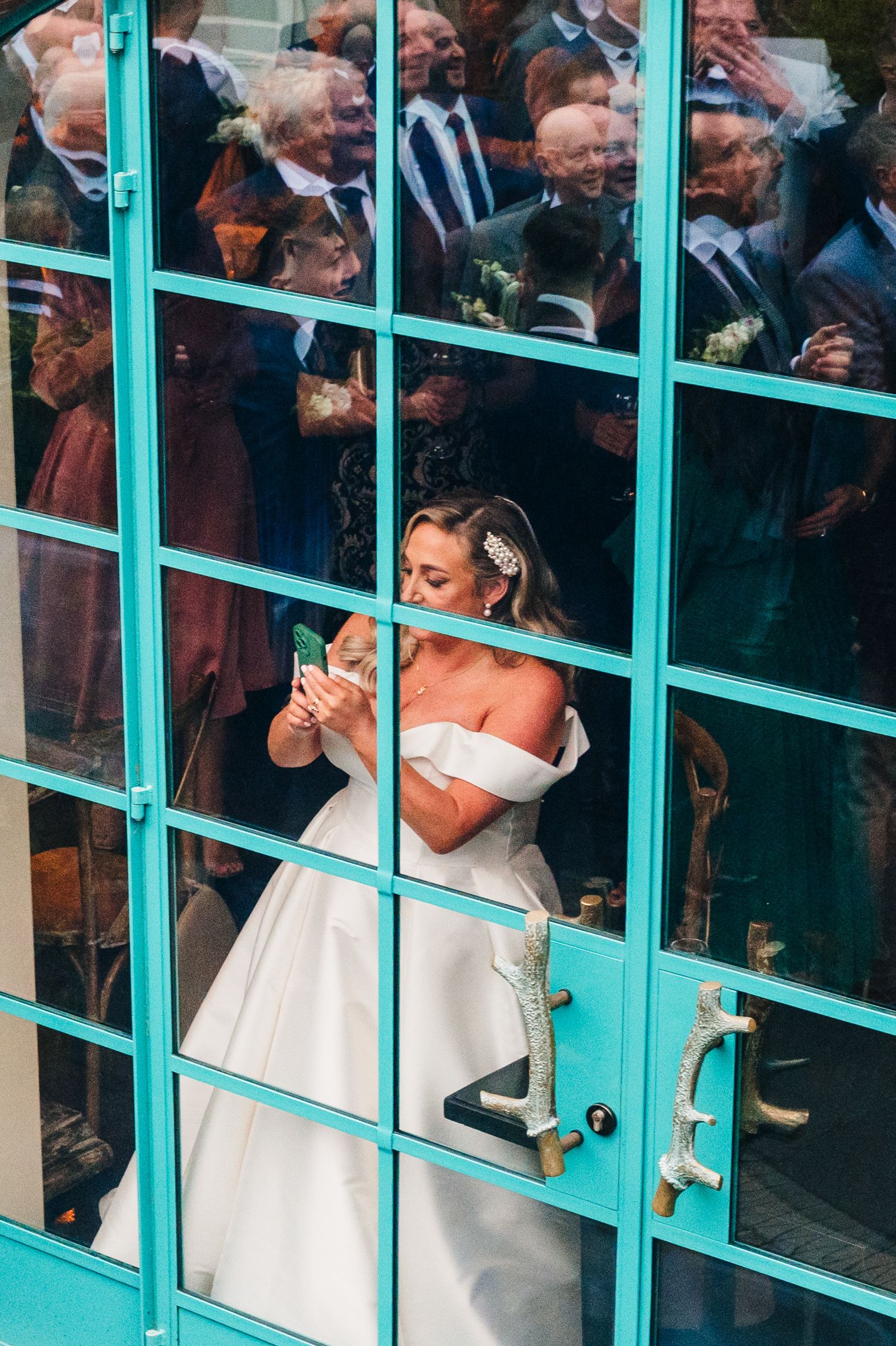 Guests peek through turquoise-framed windows during a wedding celebration.  Virginia Park Lodge Wedding Photographer Cavan Dublin Ireland