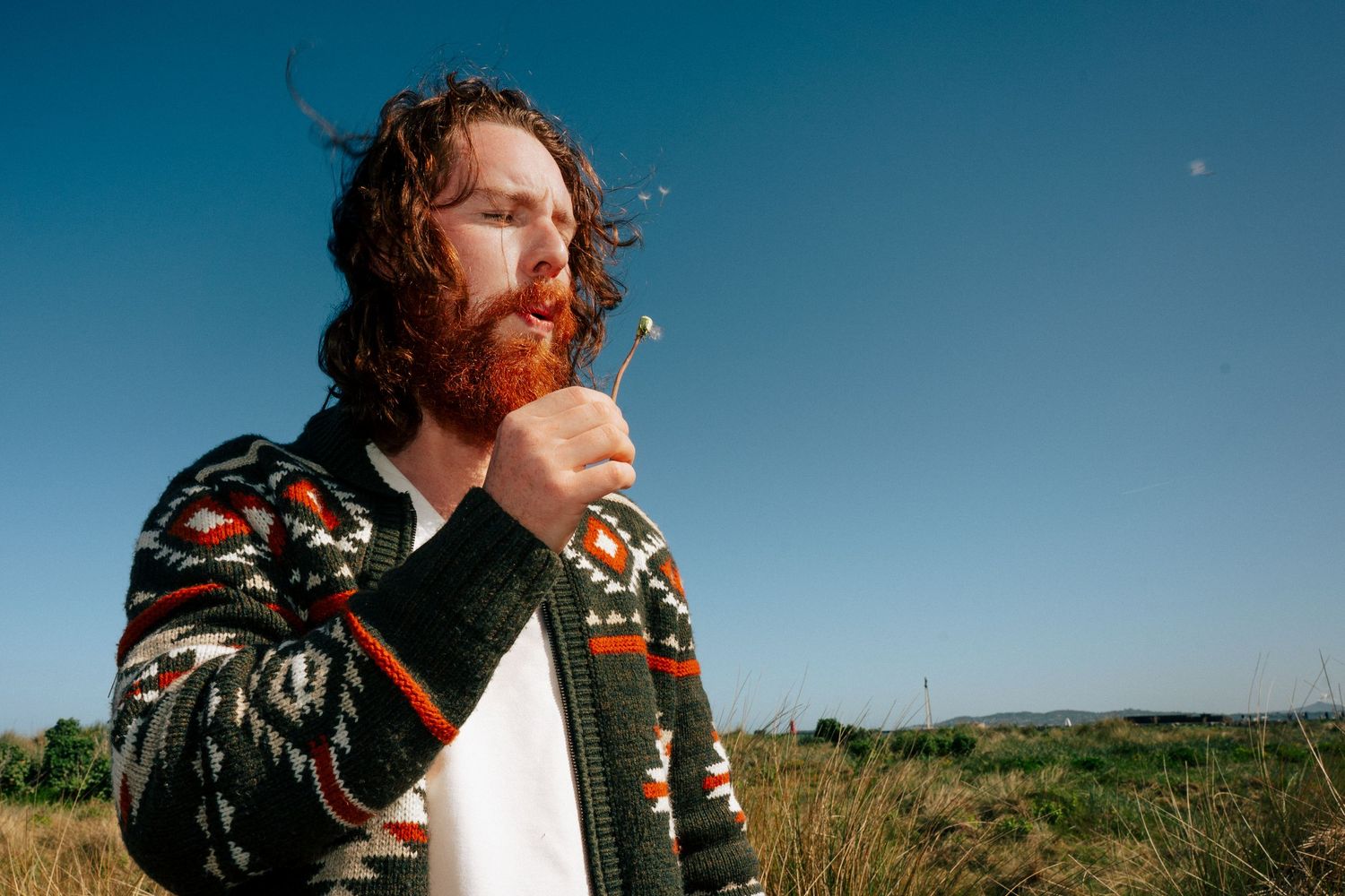 Energetic outdoor portrait against blue sky displaying floral jacket and expressive pose. PHOTOGRAPHER Dublin