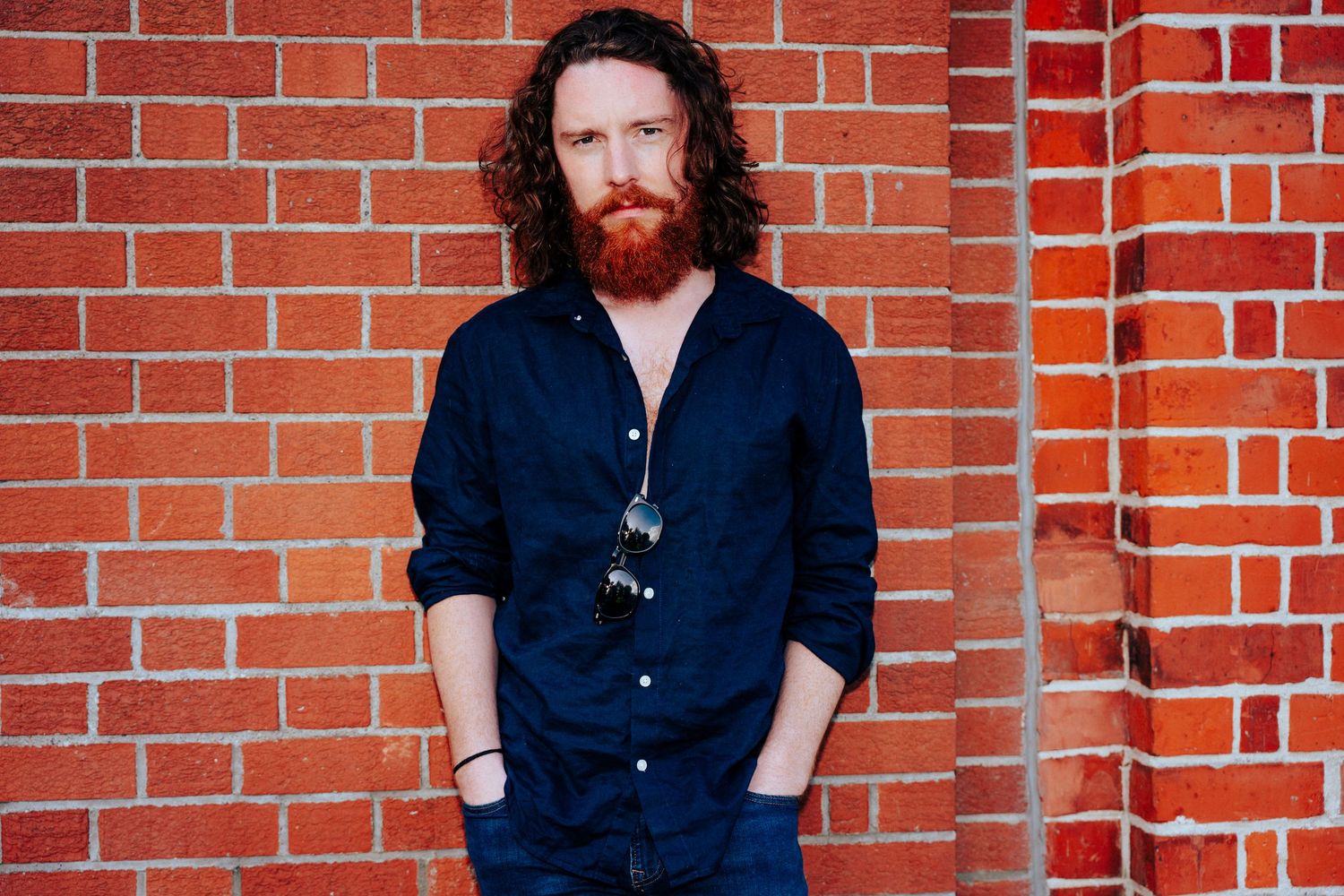 Someone in dark clothing photographed against a rustic red brick wall. PHOTOGRAPHER Dublin