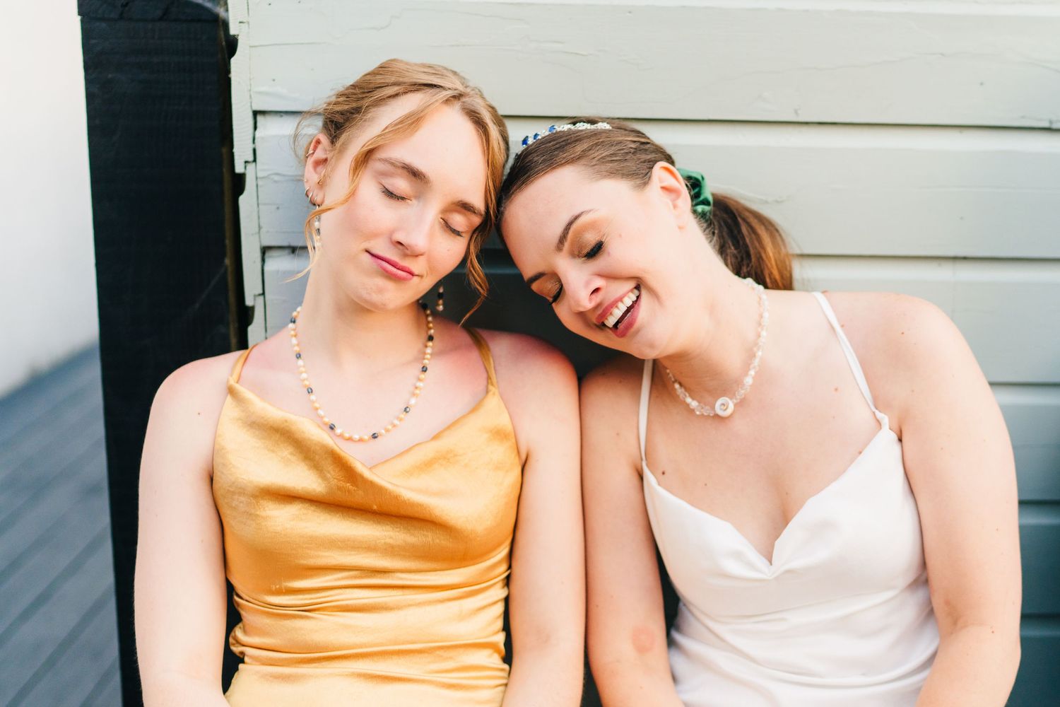 Poulaphouca Wedding photographer wicklow  Wedding party members in gold and white dresses sitting close together outdoors.