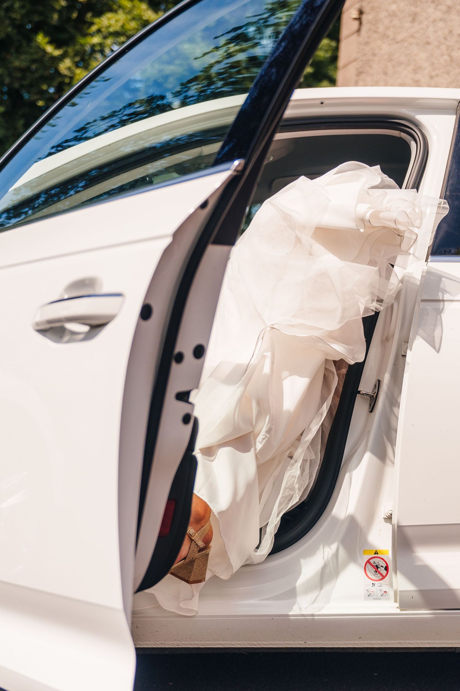Deployed airbag hanging out of open white car door showing aftermath of vehicle collision or safety system activation.Millhouse slane weddin
