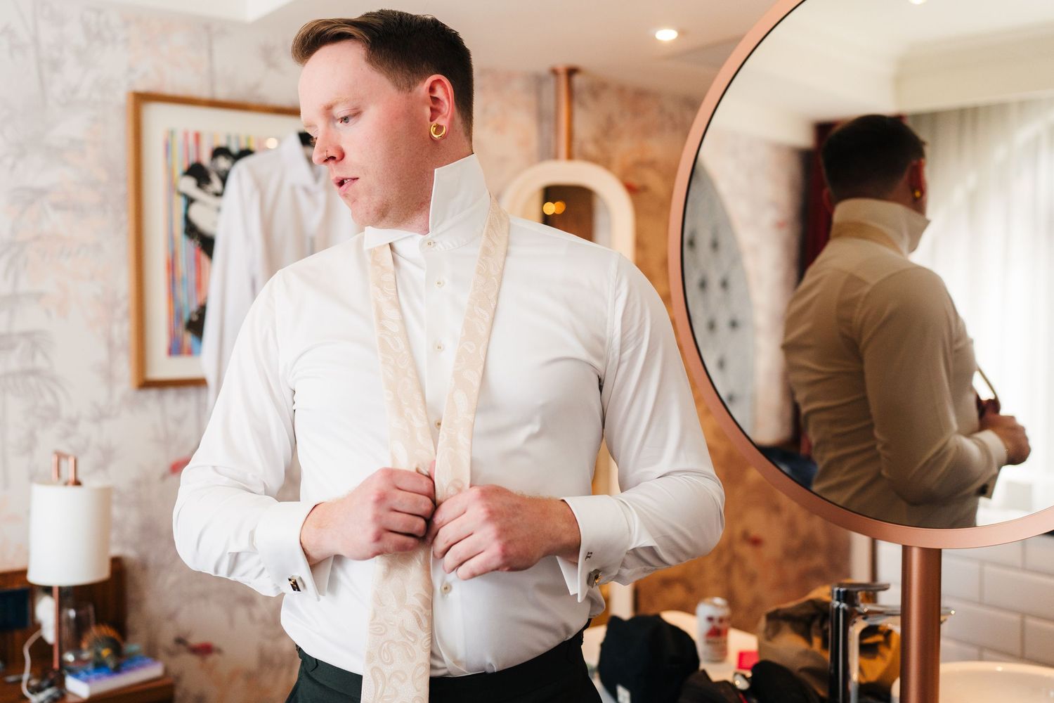 Someone adjusting a tie while getting ready in front of a mirror. PHOTOGRAPHER Dublin Ireland Wedding