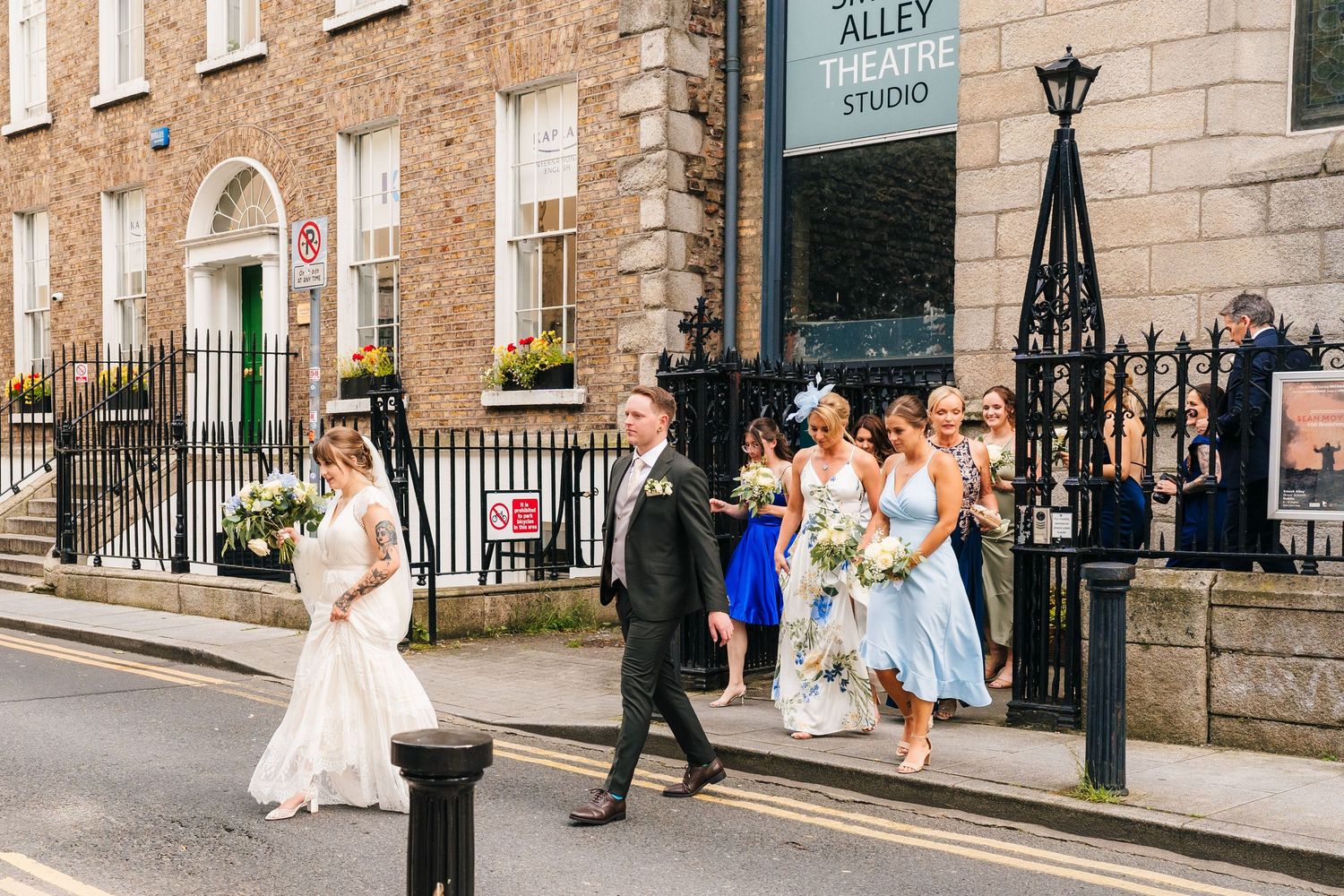 Wedding party walking along historic Dublin street with stone buildings. PHOTOGRAPHER Dublin Ireland Wedding