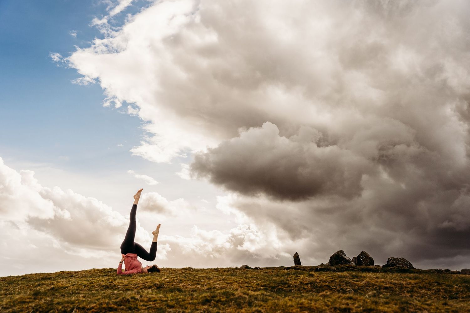 Dramatic silhouette of someone doing a handstand against stormy clouds on a hilltop. Portrait PHOTOGRAPHER Dublin