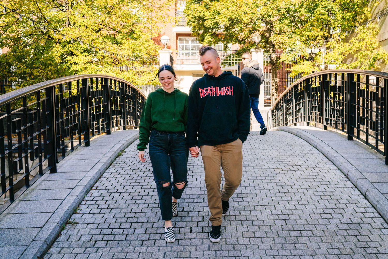 A couple walks together on a path with black railings and autumn trees. PHOTOGRAPHER Dublin Ireland