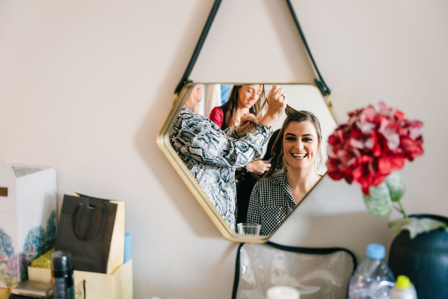 A heart-shaped wall mirror reflects a cozy interior scene with a teal vase and pink flowers visible in the room. House Dublin Wedding Photog