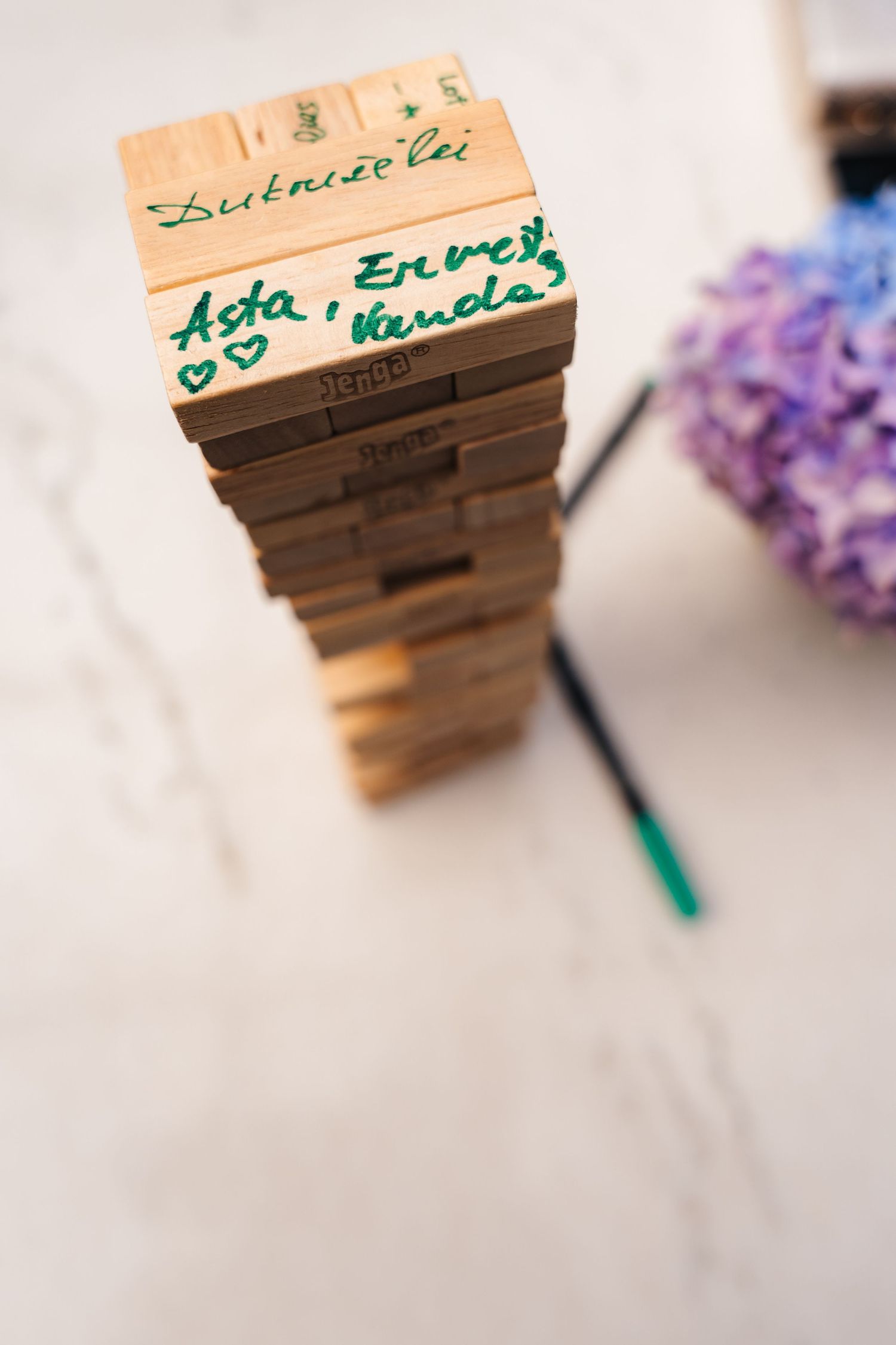 Wooden place cards with handwritten names arranged on a light surface with purple flowers. House Dublin Wedding Photographer