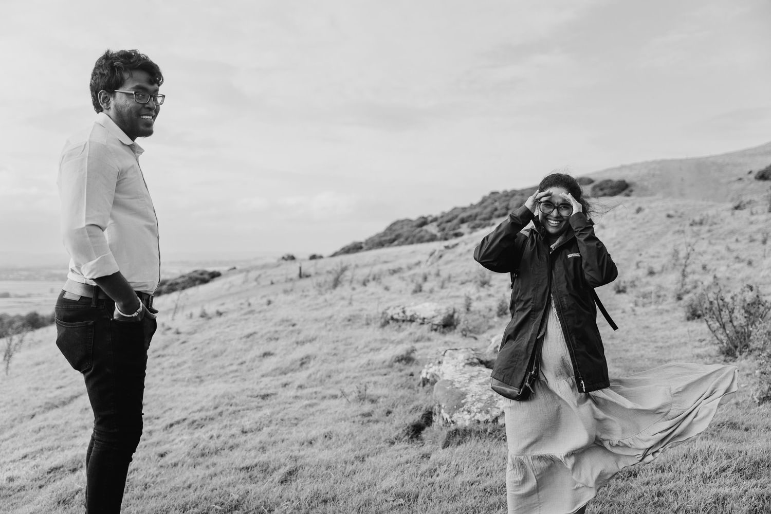 Black and white photo of couple walking together on a grassy hillside path. PHOTOGRAPHER Dublin ireland