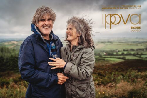 Happy couple laughing together on a hillside in moody weather. Photographer dublin ireland