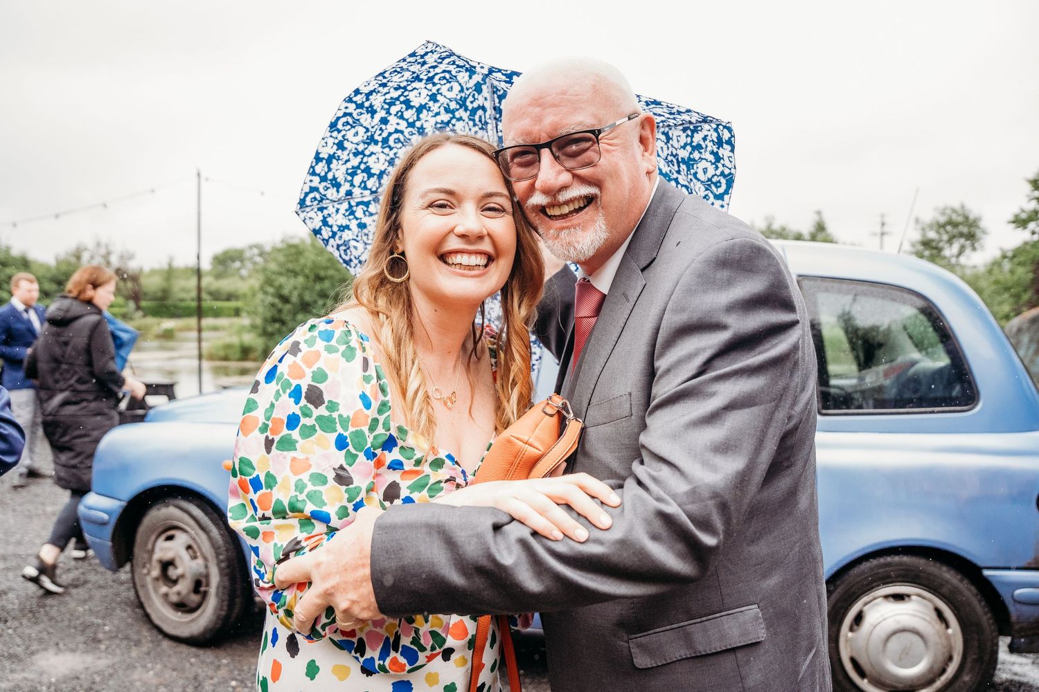 Couple shares joyful moment together outside near vintage blue car. Wedding photographer Dublin