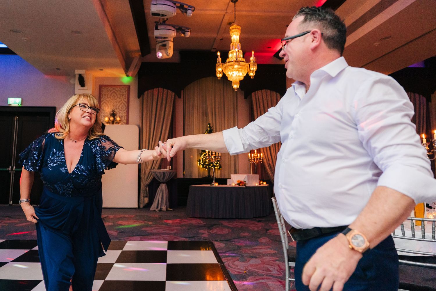 Wedding reception guests dancing on a black and white checkered dance floor under warm lighting. Wedding photographer dublin