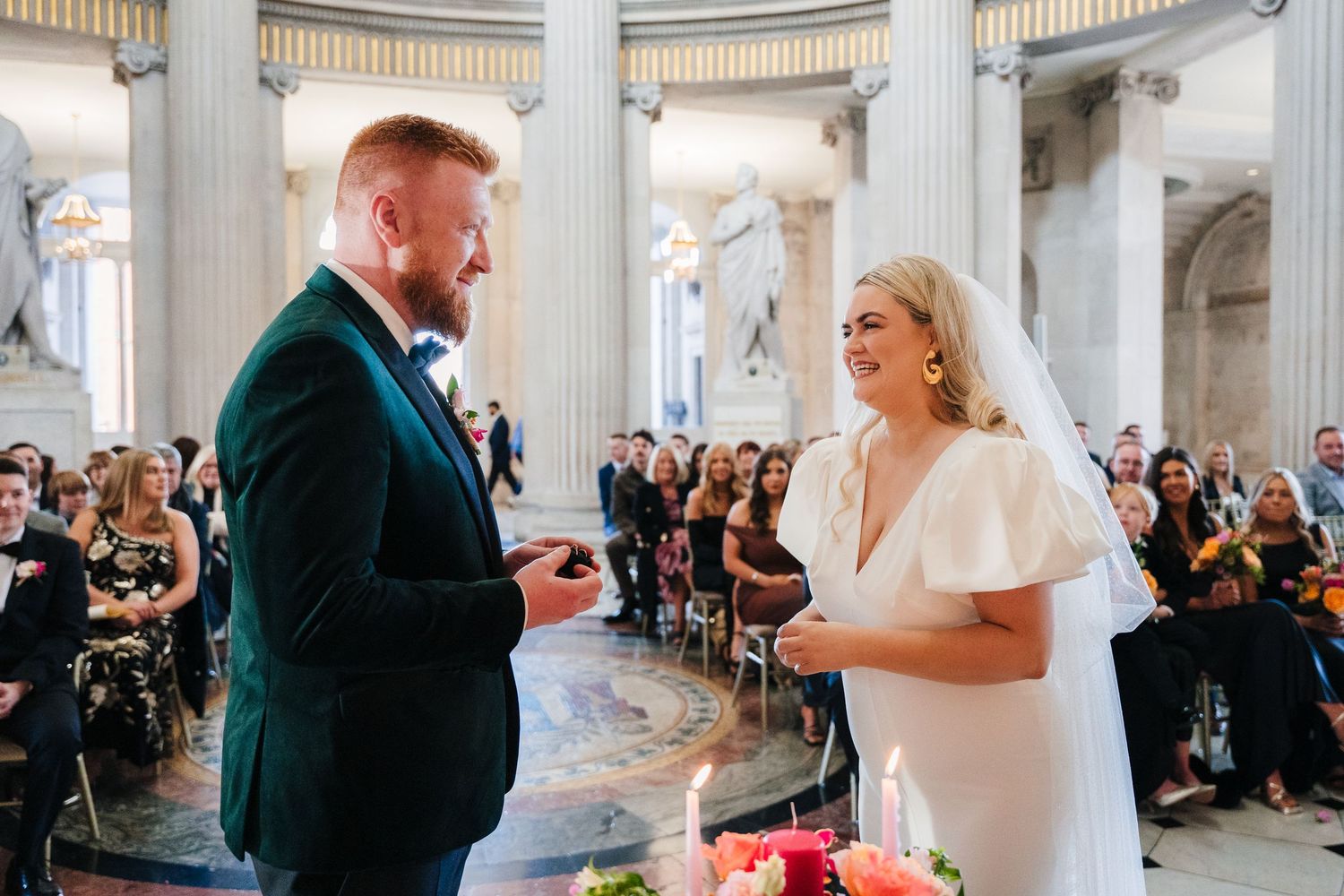 Wedding ceremony in an elegant white columned venue with guests seated in rows. Wedding photographer dublin