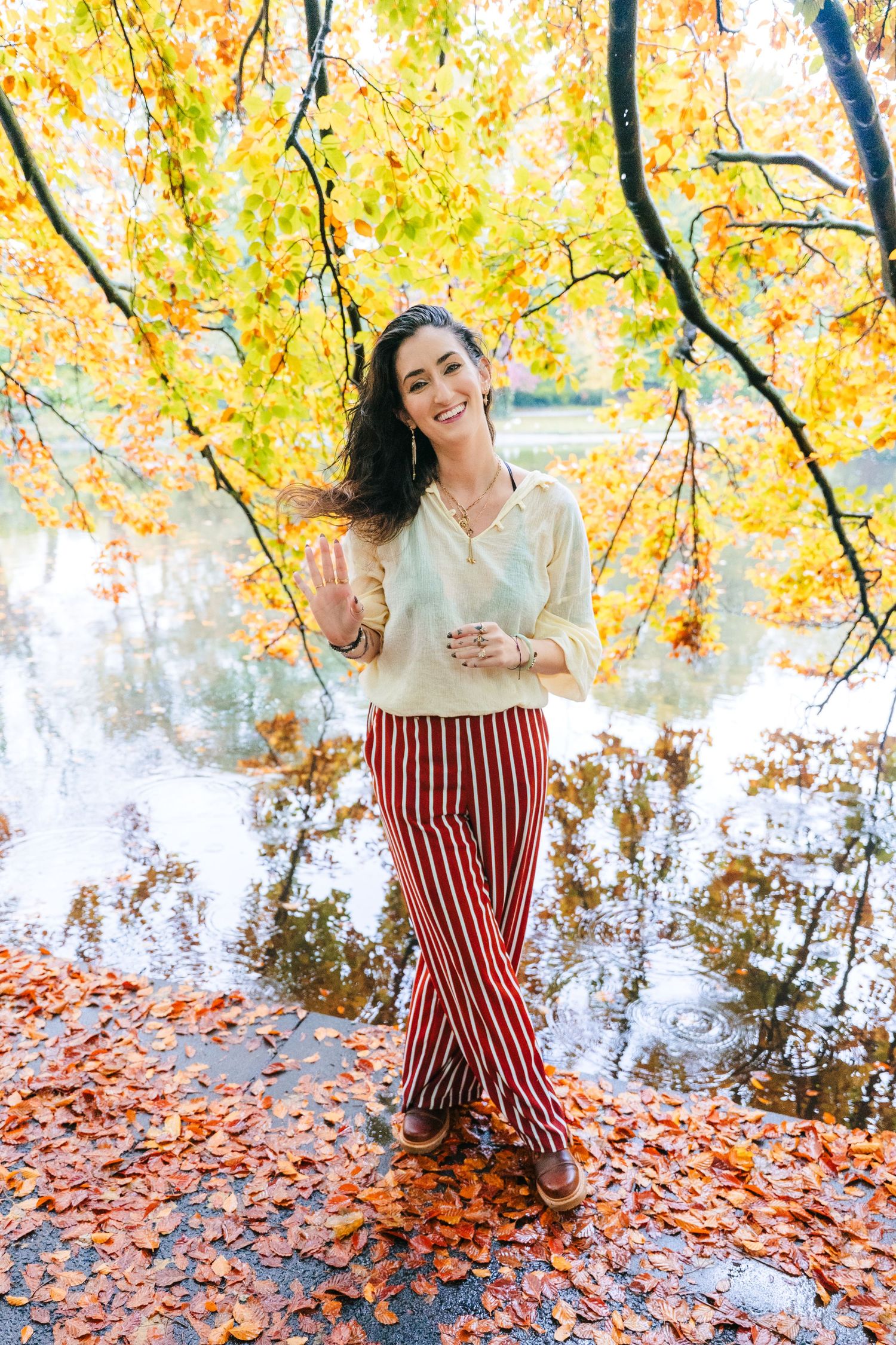 Autumn fashion shoot by water with fallen leaves and golden trees in background. professional headshots dublin photographer