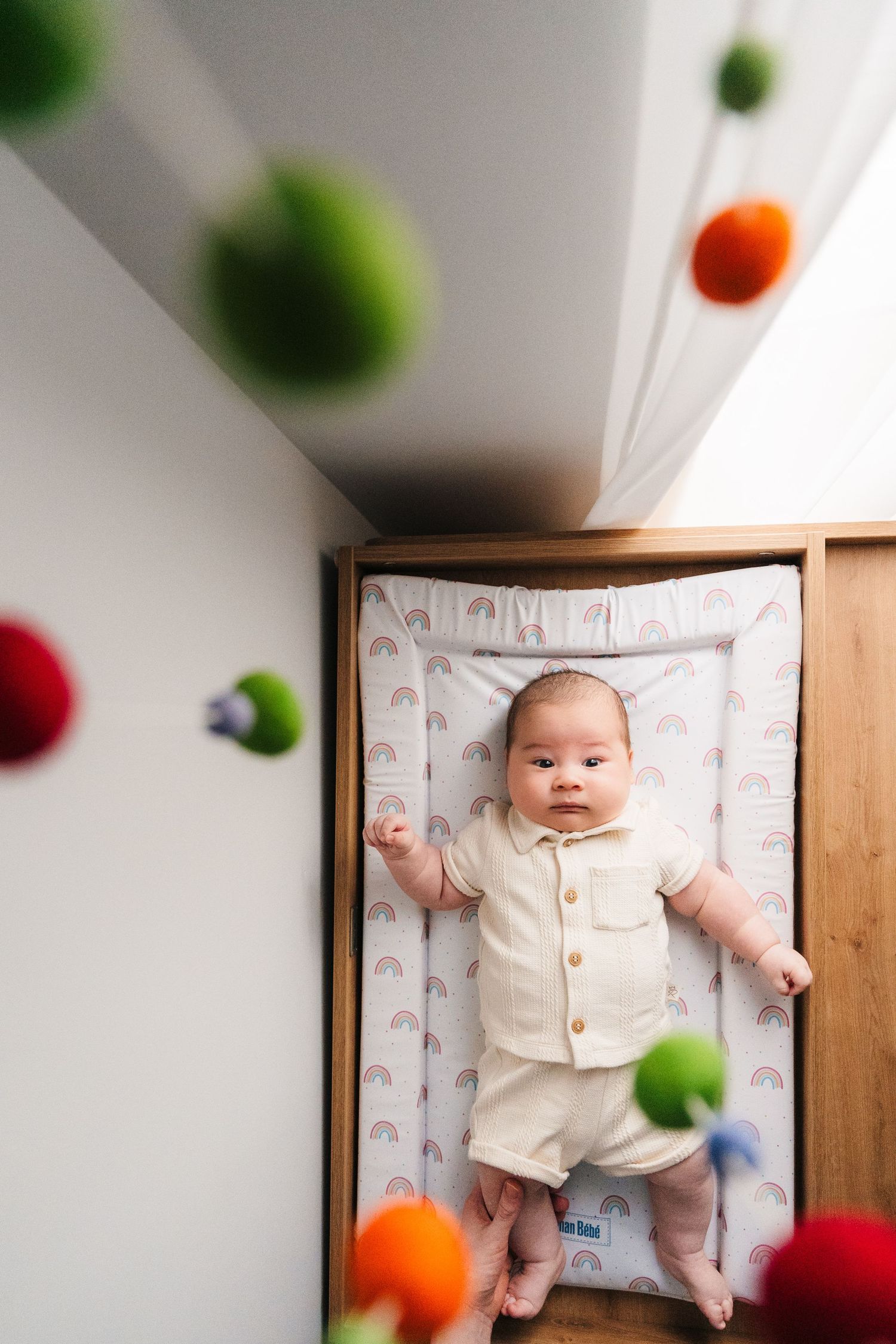 Baby on rainbow patterned blanket surrounded by colorful floating balls in artistic overhead photo. family PHOTOGRAPHER Dublin