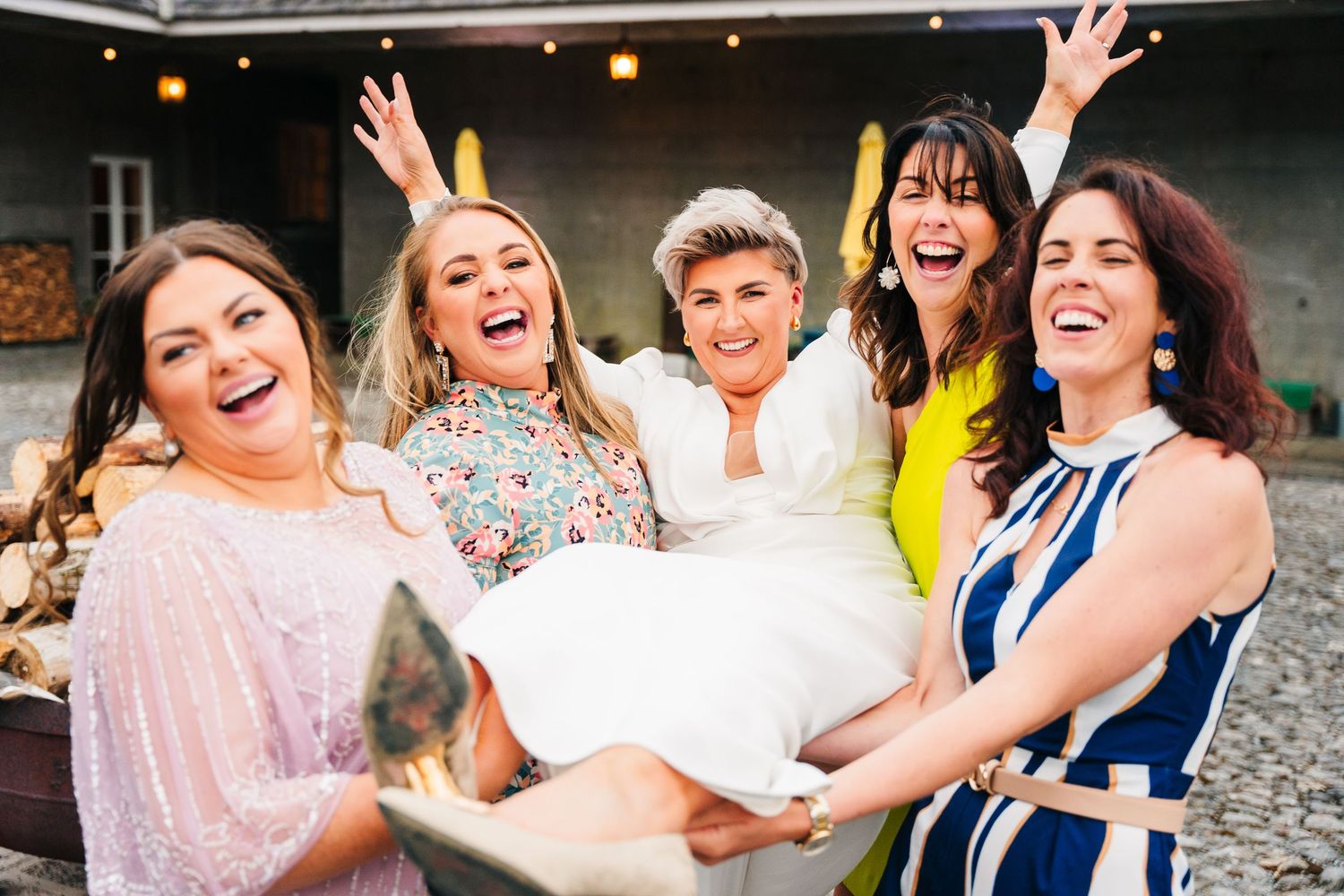 A group of wedding guests sharing joyful laughter together at an outdoor celebration. Wedding PHOTOGRAPHER Dublin