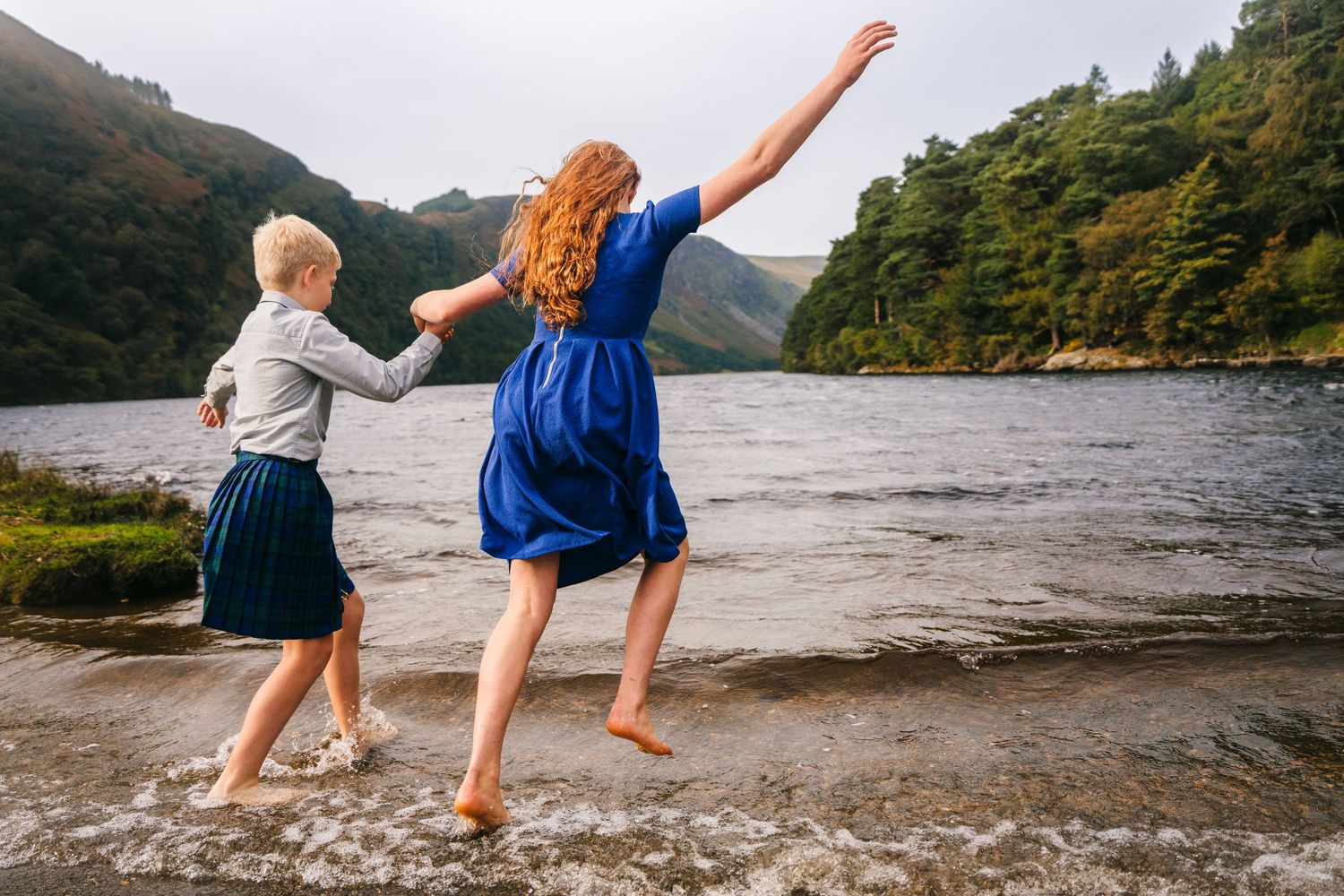 Children playing and splashing in the shallow water of a mountain lake at sunset.Family photogrAPHER DUBLIN