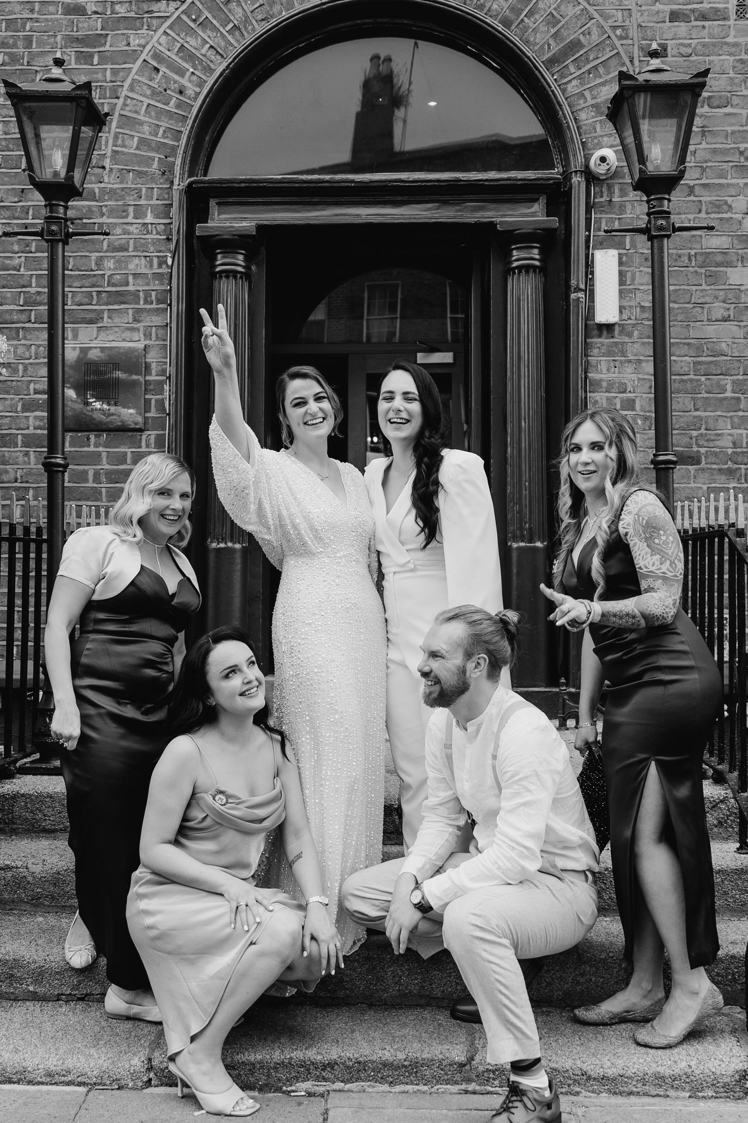 Black and white photos of wedding party members posing playfully on steps of brick building. House Dublin Wedding Photographer