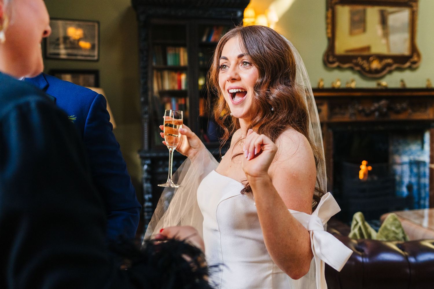 Castle Leslie Wedding Photographer Dublin Bride in strapless dress celebrates with champagne during wedding reception indoors.