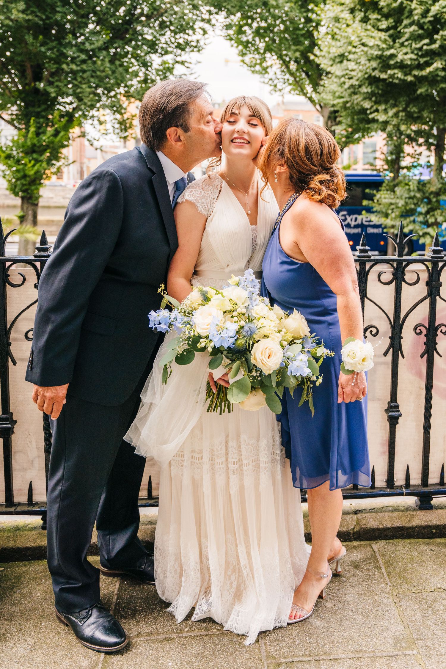 A sweet moment captured with a bride holding a white and blue floral bouquet on her wedding day. PHOTOGRAPHER Dublin Ireland Wedding