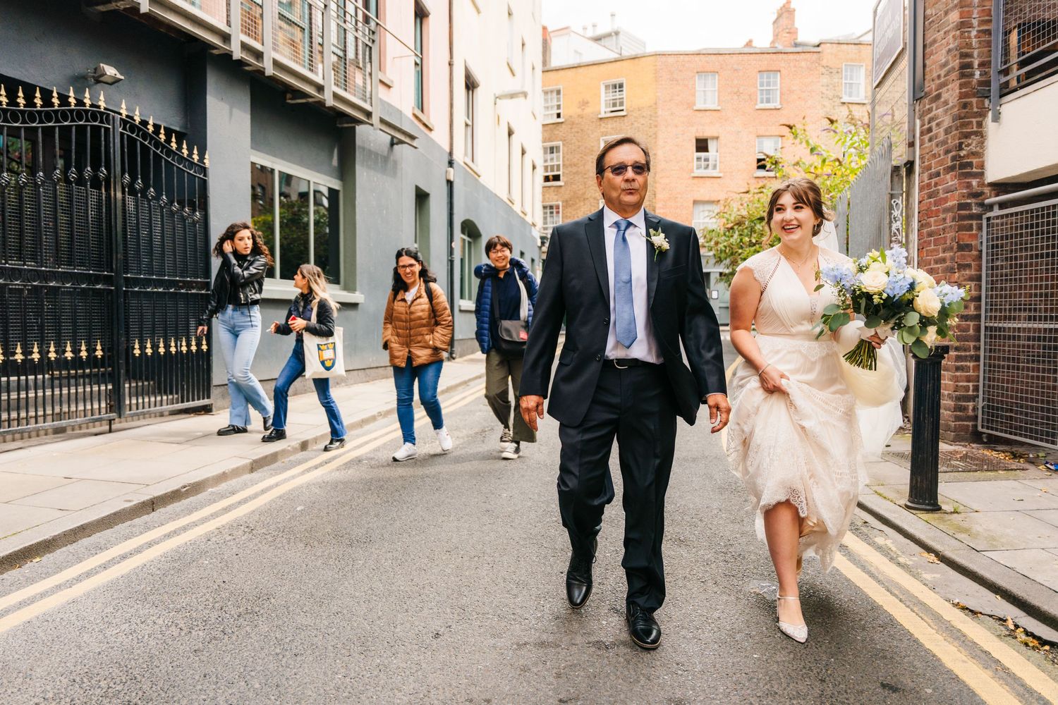 Wedding couple walking down urban alley with brick buildings. PHOTOGRAPHER Dublin Ireland Wedding