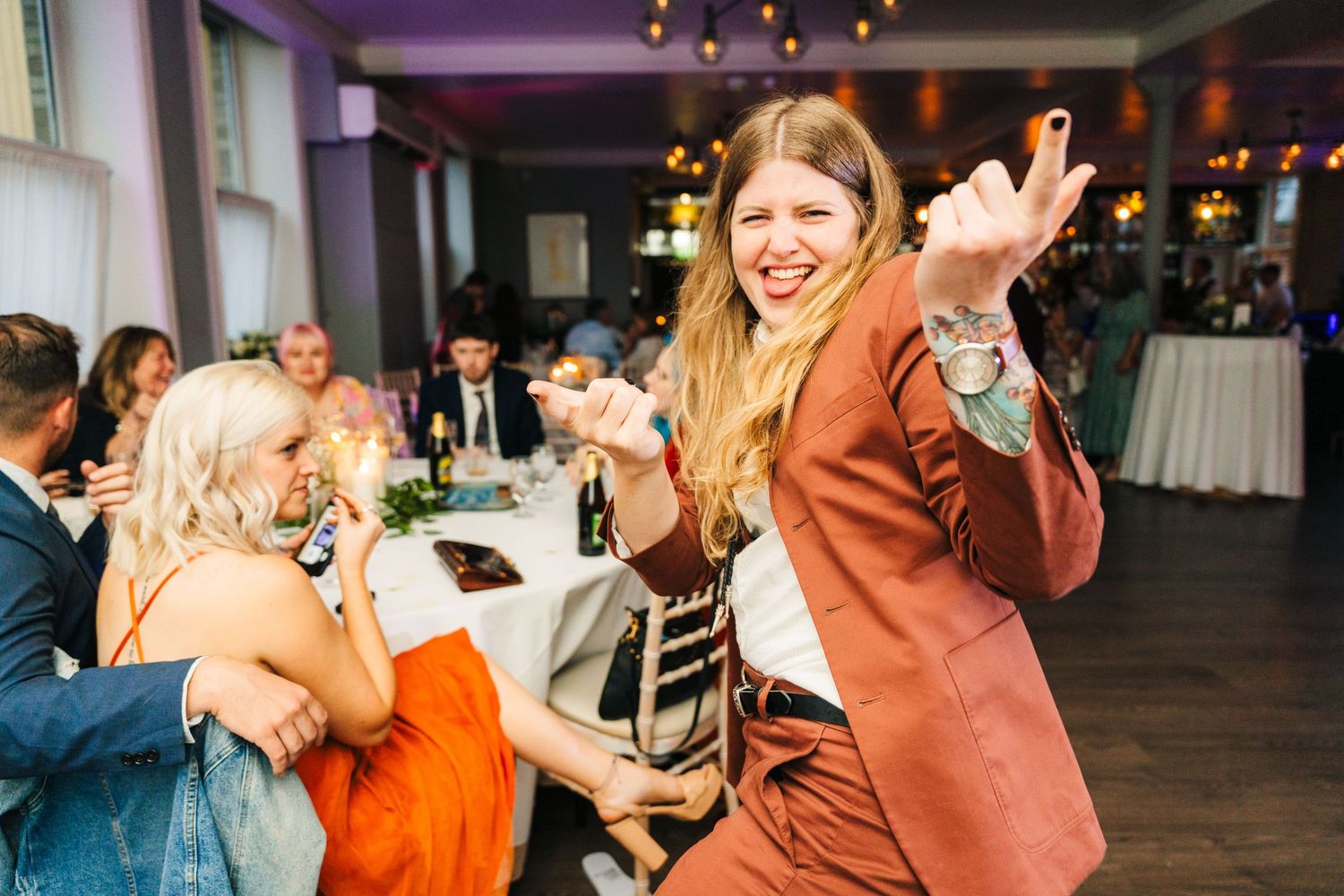 Wedding guest in a rust-colored suit celebrates enthusiastically during the reception. PHOTOGRAPHER Dublin Ireland Wedding