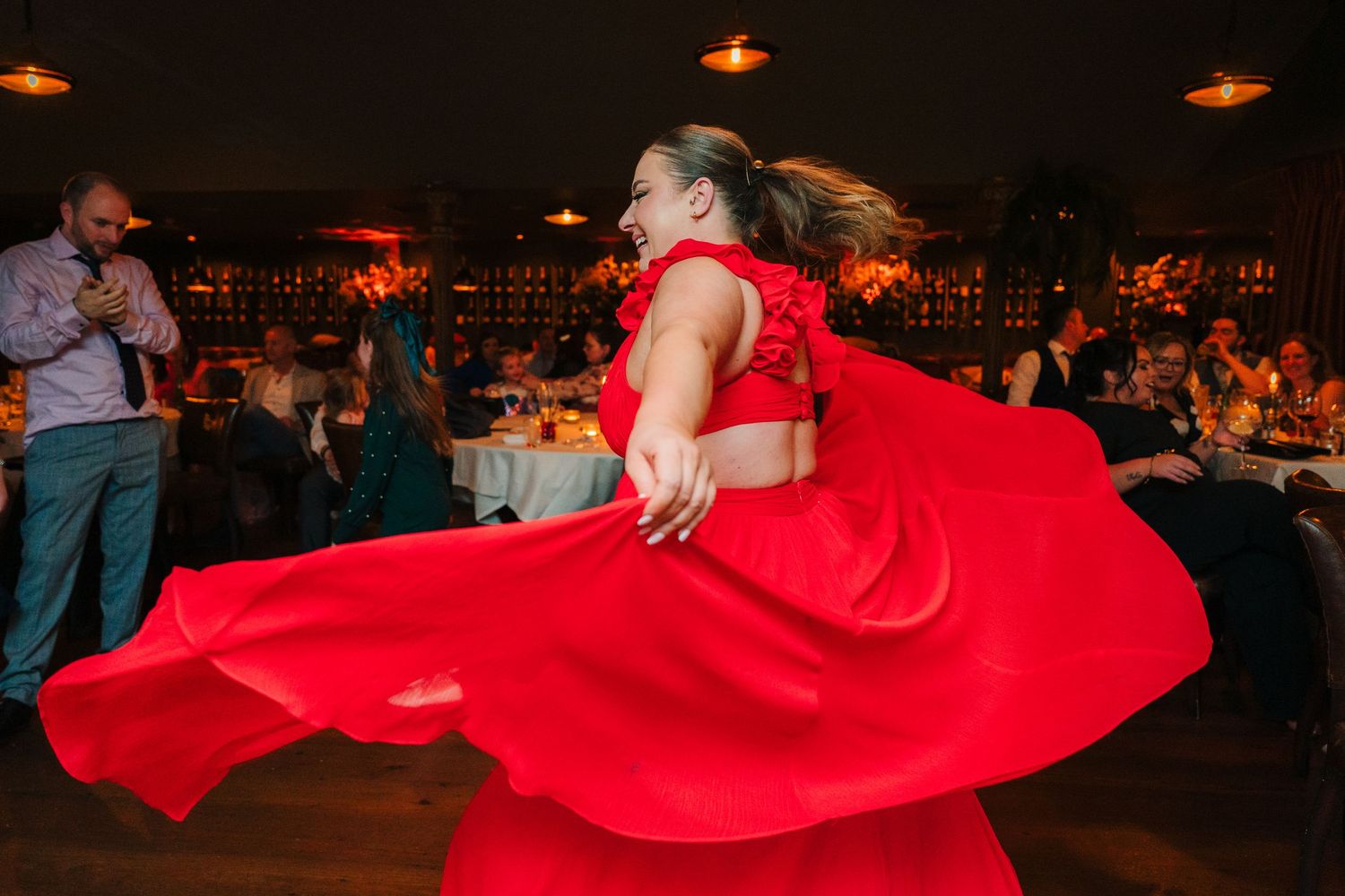 A dancer in a flowing red dress spins dramatically on a dark dance floor. Marco Pierre Dublin Wedding Photographer