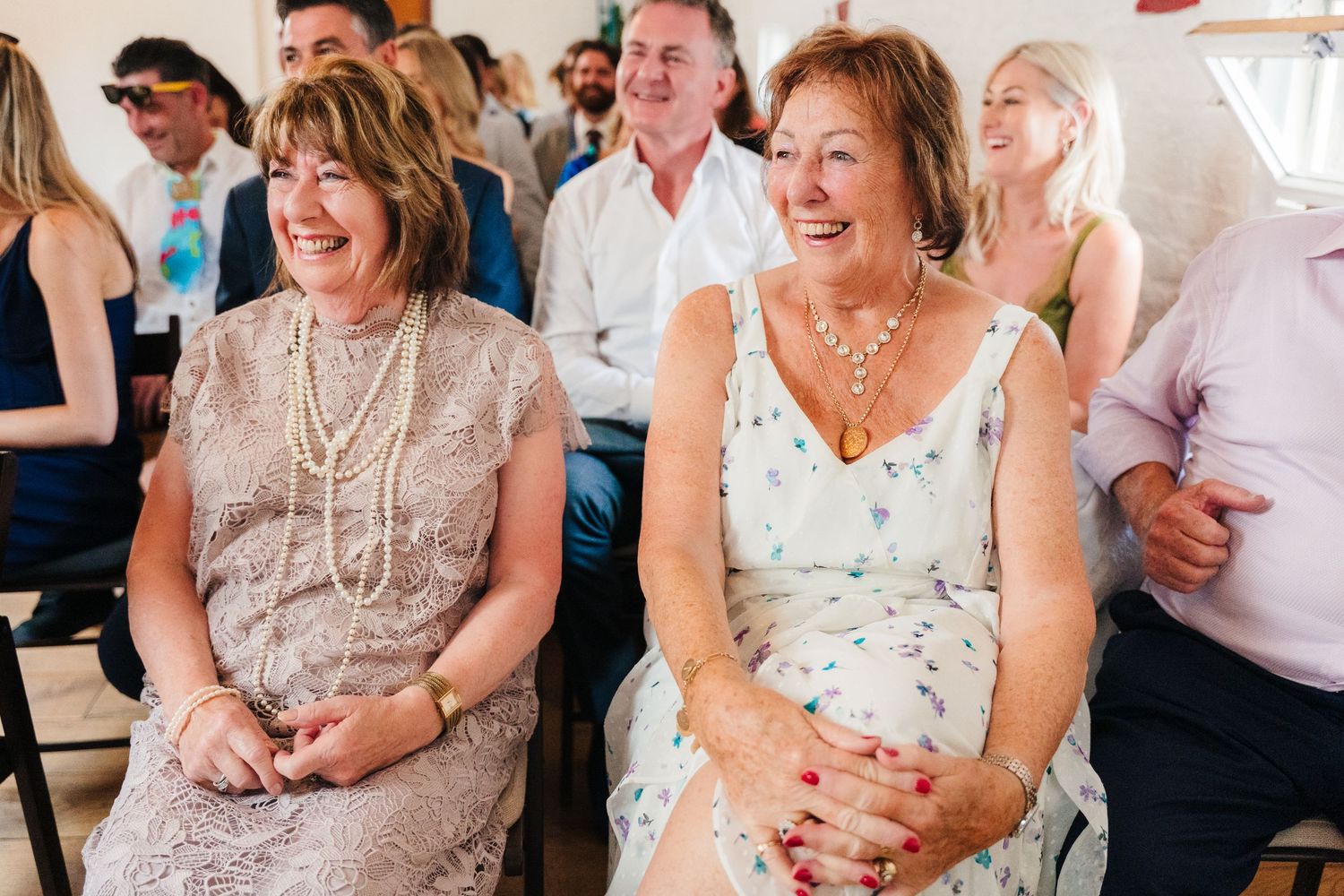 Two women in formal attire laughing together during a wedding celebration. Same sex wedding PHOTOGRAPHER Dublin
