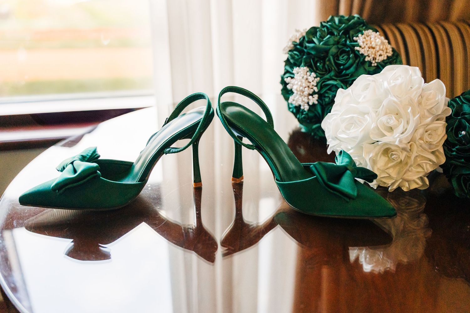 Elegant green velvet wedding shoes displayed with white floral decorations on a wooden surface.  Wedding PHOTOGRAPHER Trim Castle
