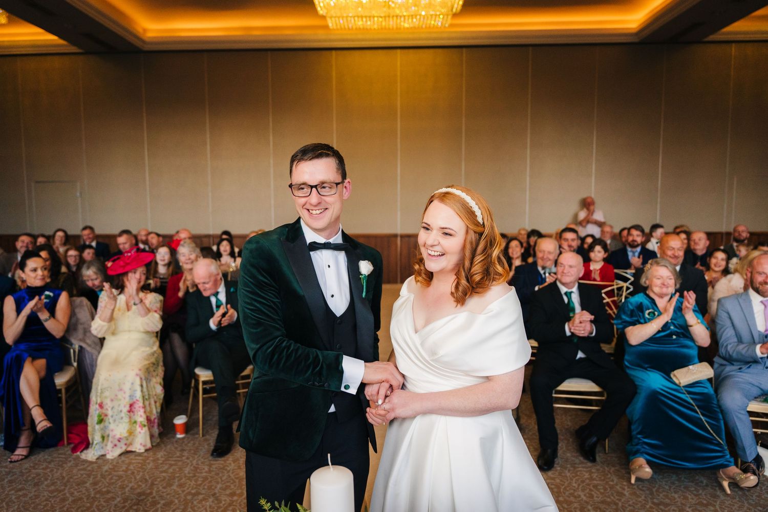 Panoramic view of wedding reception hall with chandeliers and guests watching celebration.  Wedding PHOTOGRAPHER Trim Castle