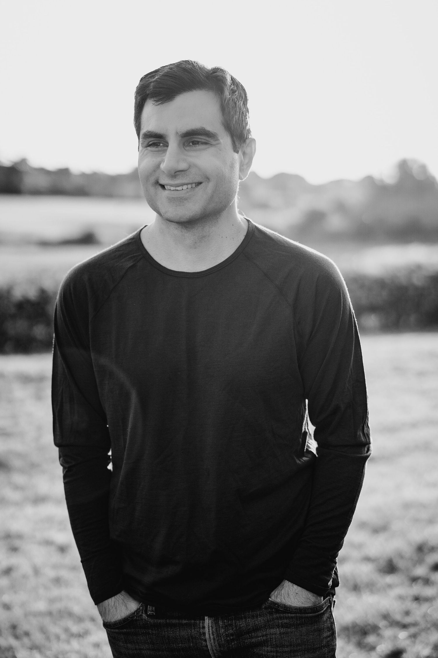 Black and white portrait of someone wearing a dark long sleeve shirt and jeans standing outdoors in natural light. PHOTOGRAPHER Dublin irela