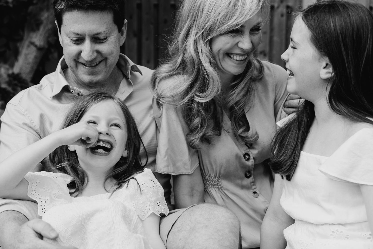 Black and white candid photo capturing a joyful family moment with everyone laughing together outdoors. family PHOTOGRAPHER Dublin