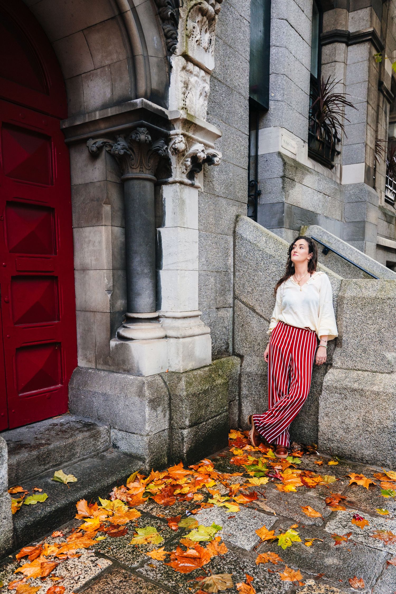 Autumn fashion shoot with red striped pants and white blouse against stone architecture. professional headshots dublin photographer
