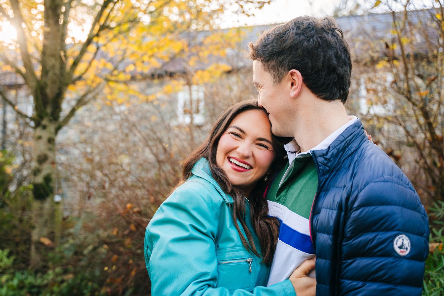 A couple shares joyful moments together outdoors during autumn with yellow foliage in the background. engagement photographer dublin