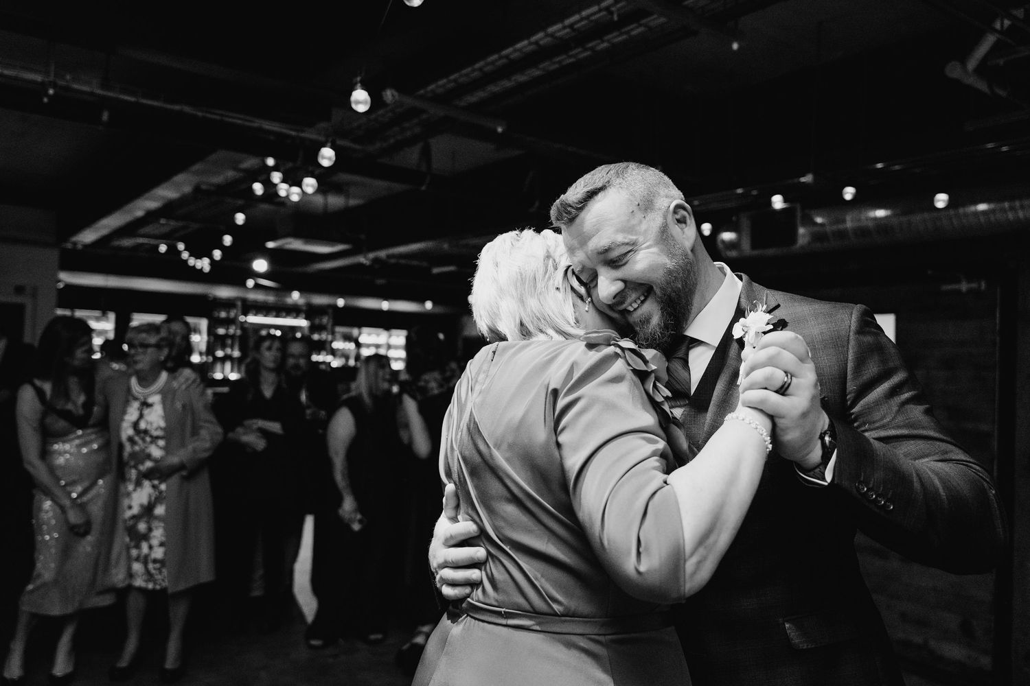 A black and white photo of a couple dancing together at an indoor reception venue. Dublin wedding photogrAPher