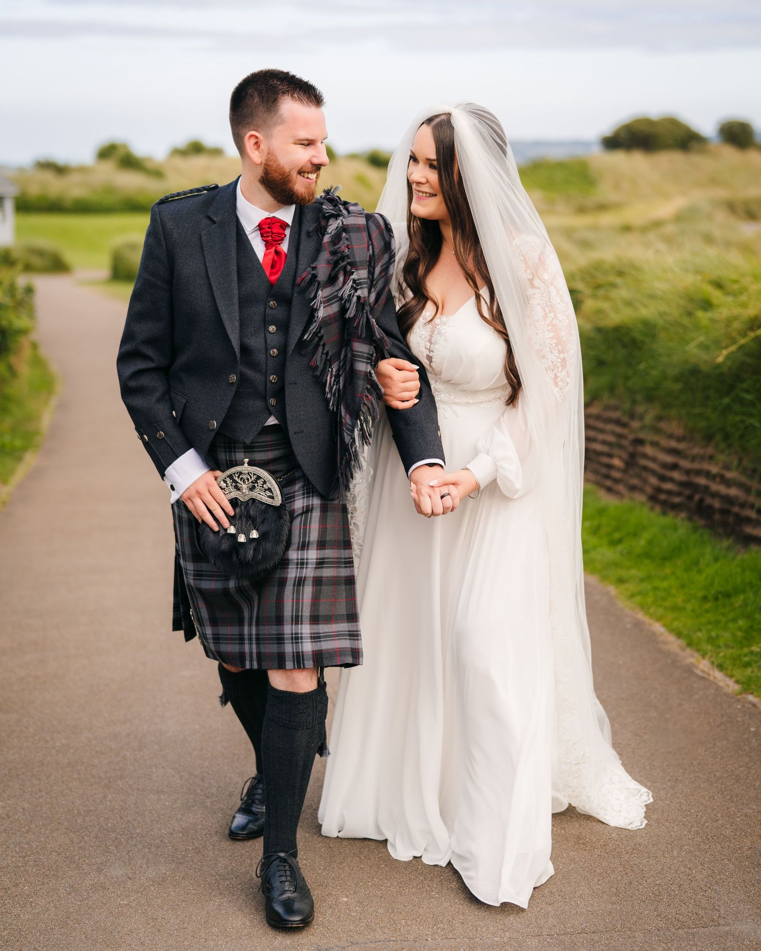 A couple in wedding attire sharing a joyful moment together on a paved path outdoors. wedding photographer dublin meath