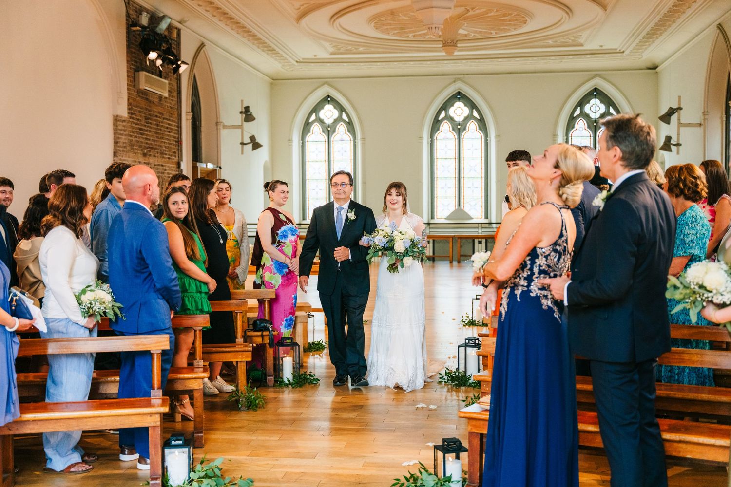 Wedding ceremony inside historic chapel with arched gothic windows and wooden pews. PHOTOGRAPHER Dublin Ireland Wedding