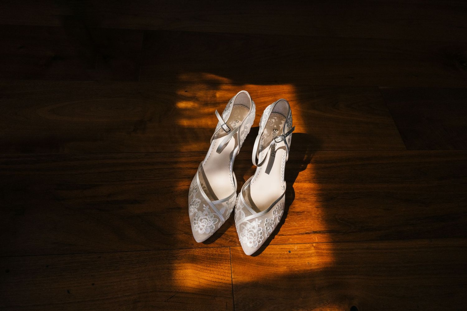 White bridal shoes against dark wood flooring with dramatic lighting. PHOTOGRAPHER Dublin Ireland Wedding