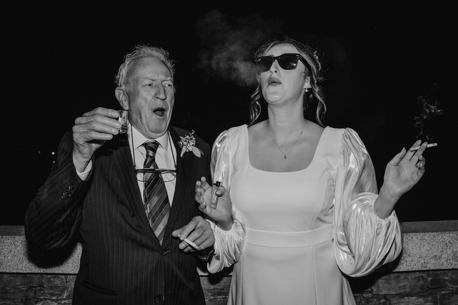 Black and white photo of two wedding guests sharing a smoke break outdoors at night.Wedding Photography Trim Castle Ireland