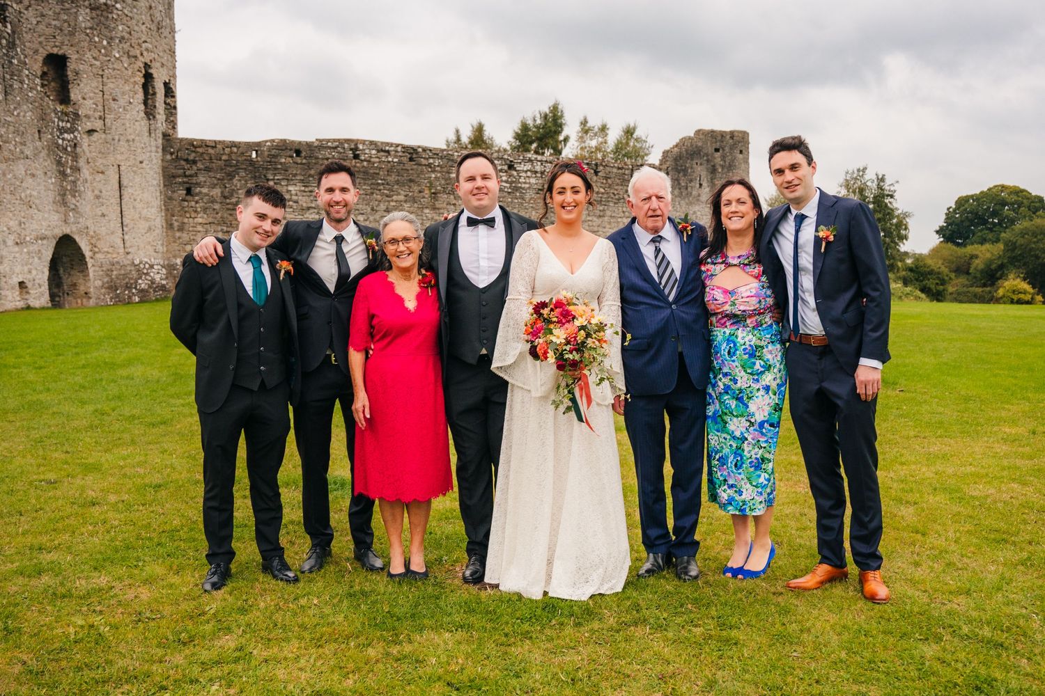 Wedding party group photo in front of an ancient stone castle on a cloudy day. Wedding Photography Trim Castle Ireland