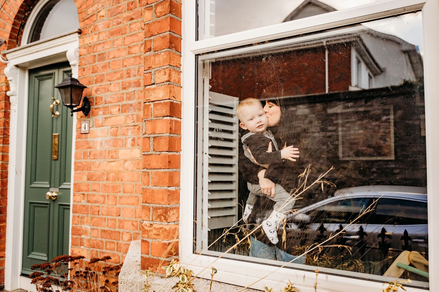 Two white owls fly and perch near a brick wall with windows, displaying their majestic wingspan in flight.  Family PHOTOGRAPHER Dublin