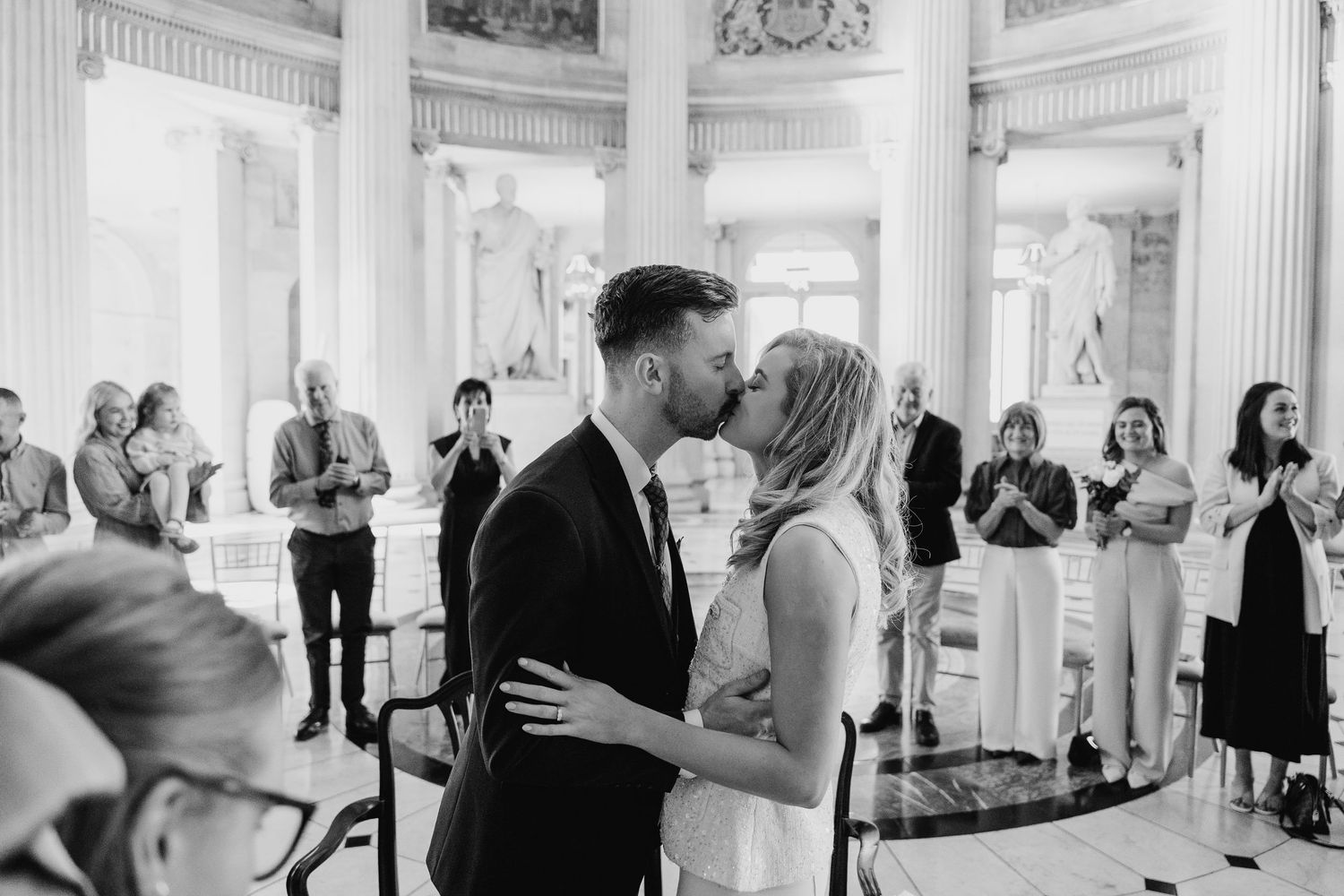 Grand room with neoclassical columns and guests gathered for a celebration. City Hall Dublin wedding photogrAPher