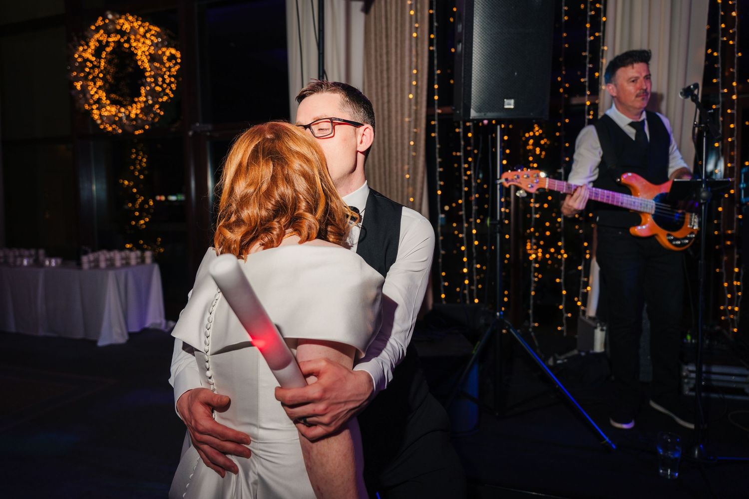 A couple shares an intimate slow dance at their reception with fairy lights in the background.  Wedding PHOTOGRAPHER Trim Castle