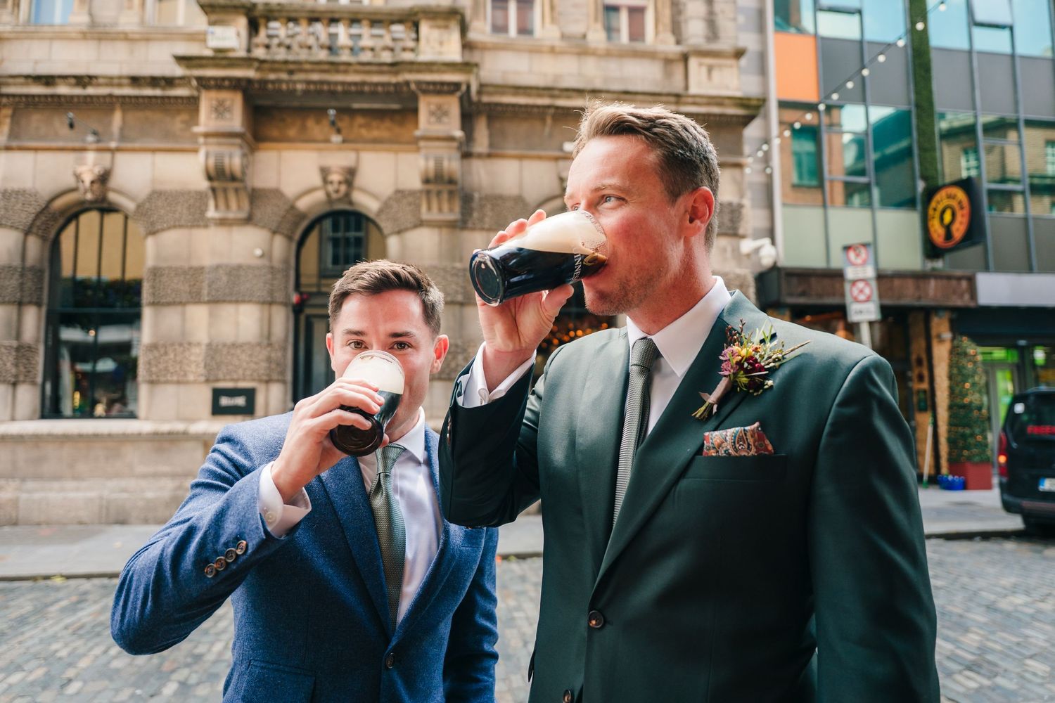 Groomsmen line up in their formal suits and perform a synchronized salute outside a stone building. Same sex wedding PHOTOGRAPHER Dublin