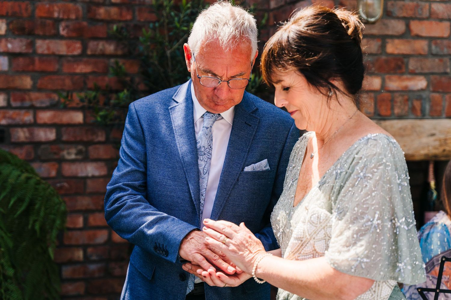 Couple in wedding attire stands affectionately together against a brick wall backdrop. House Dublin Wedding Photographer