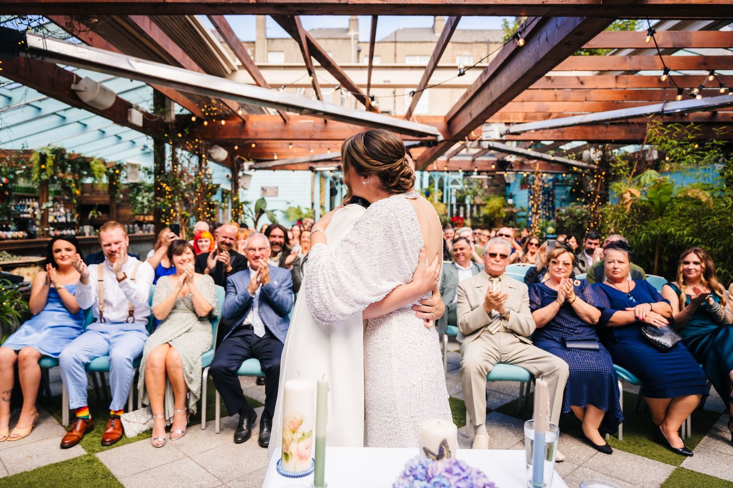 Wedding ceremony attendees seated outdoors under a covered patio applaud the couple.House Dublin Wedding Photographer