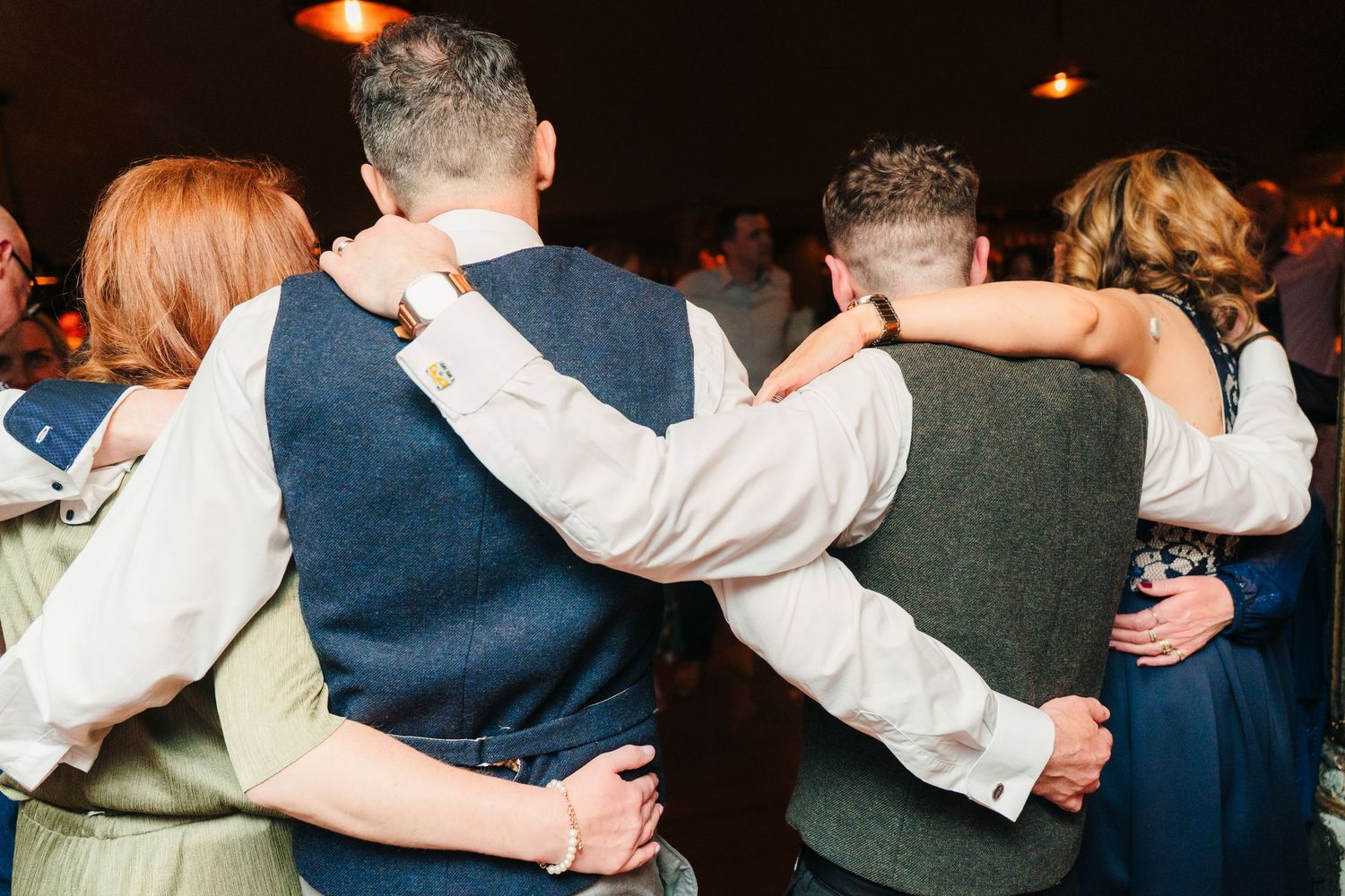 Guests embrace in a group hug during a wedding reception celebration. Marco Pierre Dublin Wedding Photographer