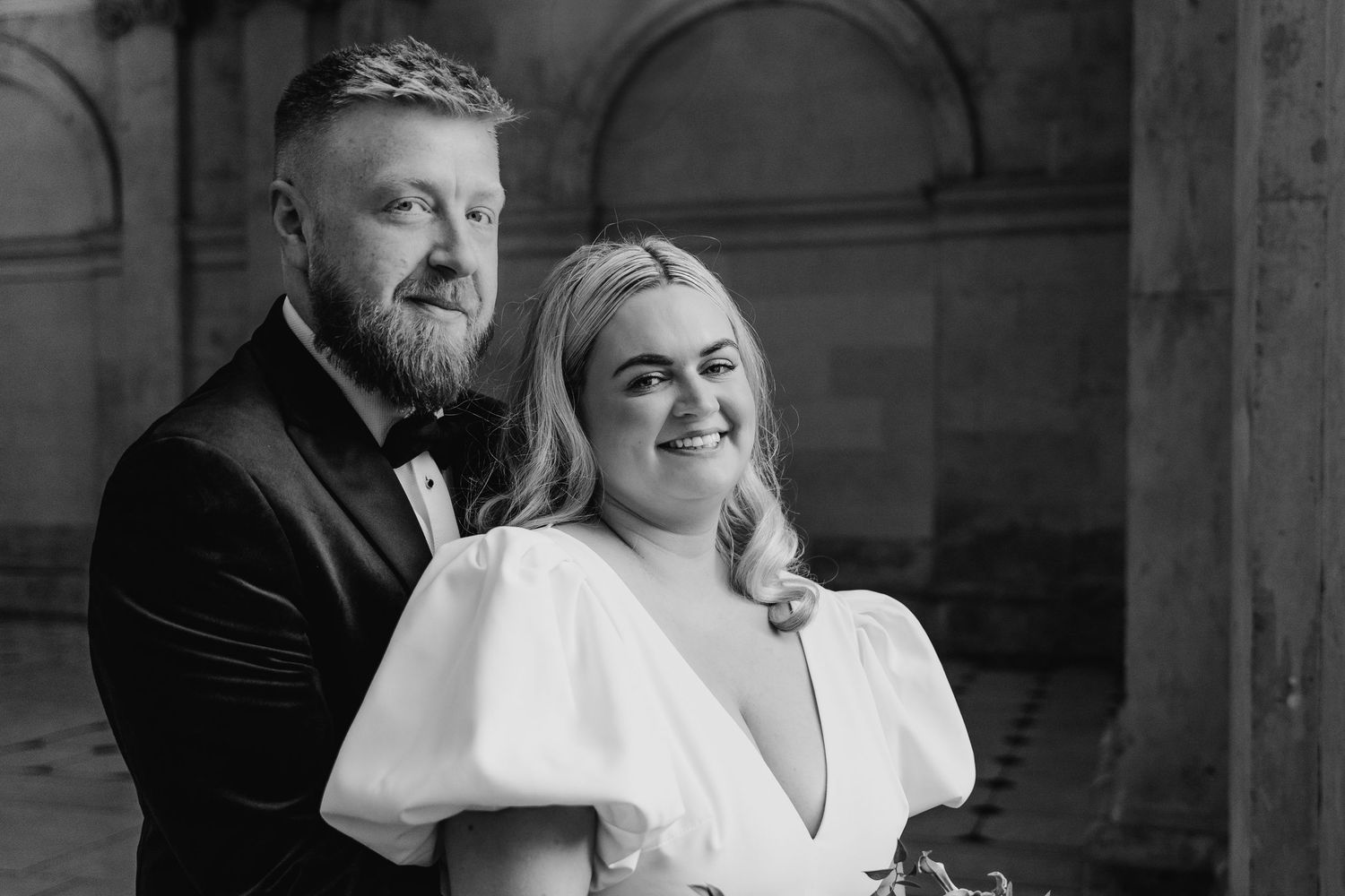 Formal black and white portrait of a couple in wedding attire against stone architecture. Wedding photographer dublin